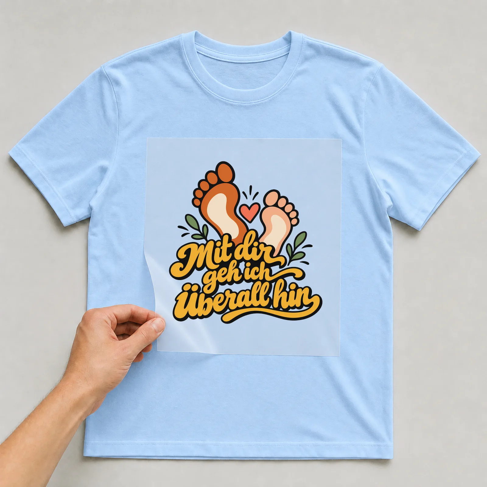 Bügelbild „Mit dir geh ich überall hin“ auf hellblauem T-Shirt, Folie wird aufgelegt