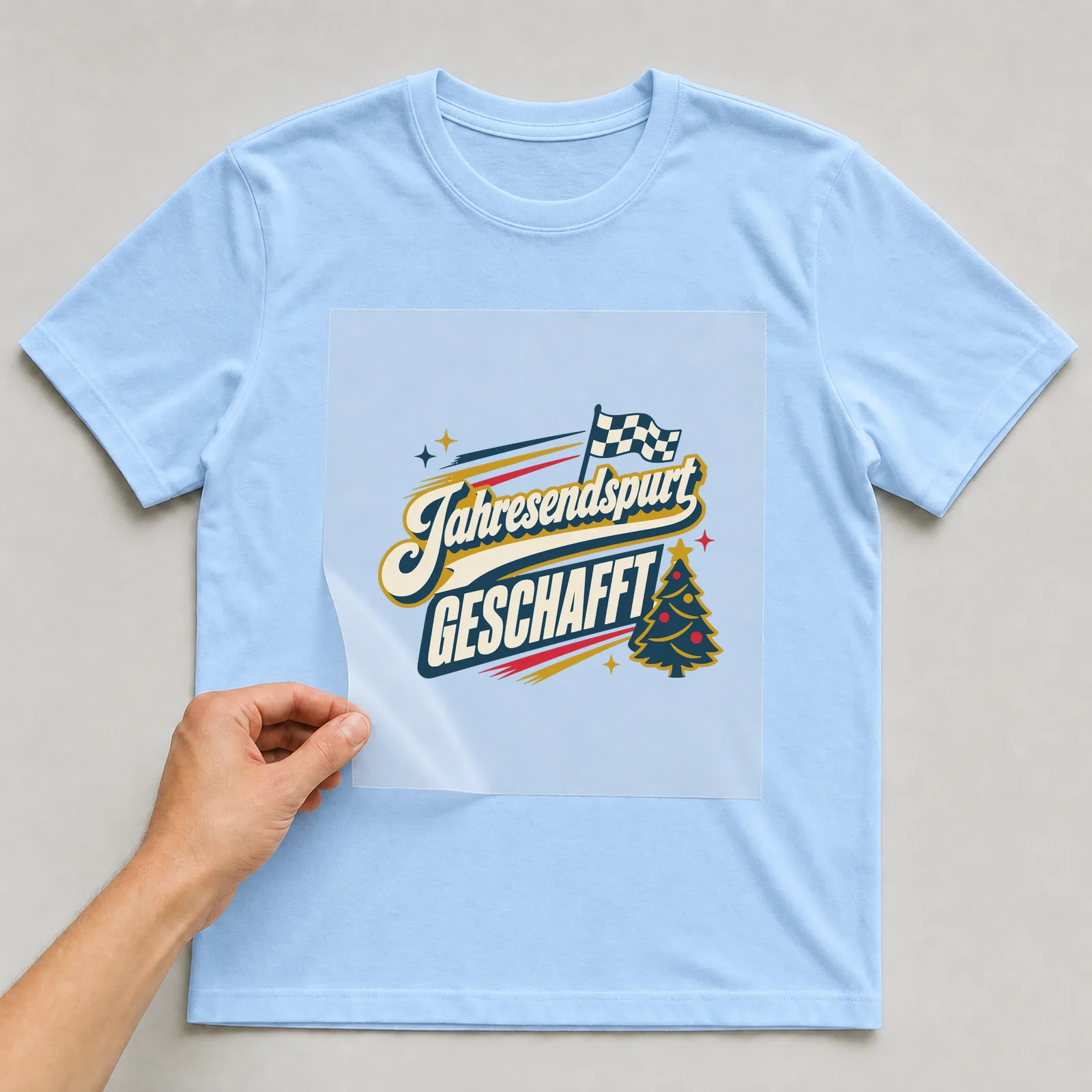 Bügelbild Jahresendspurt geschafft auf hellblauem T-Shirt, Folie wird aufgelegt