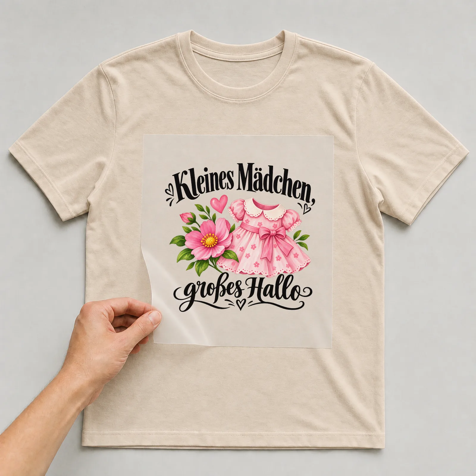 Bügelbild „Kleines Mädchen, großes Hallo“ auf beigem T-Shirt, Folie wird aufgelegt