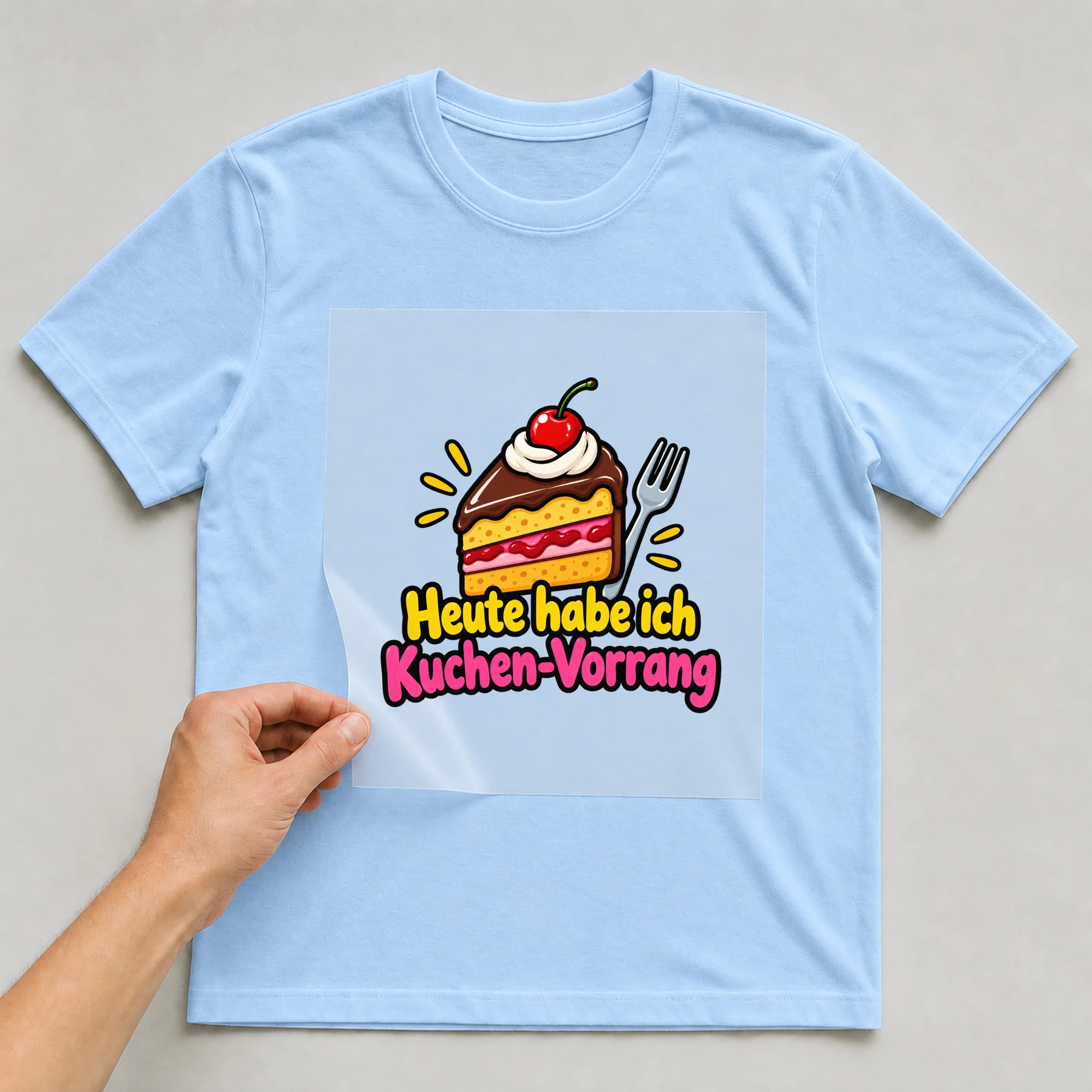 Bügelbild „Heute habe ich kuchen vorrang“ auf babyblauem T-Shirt, Folie wird aufgelegt