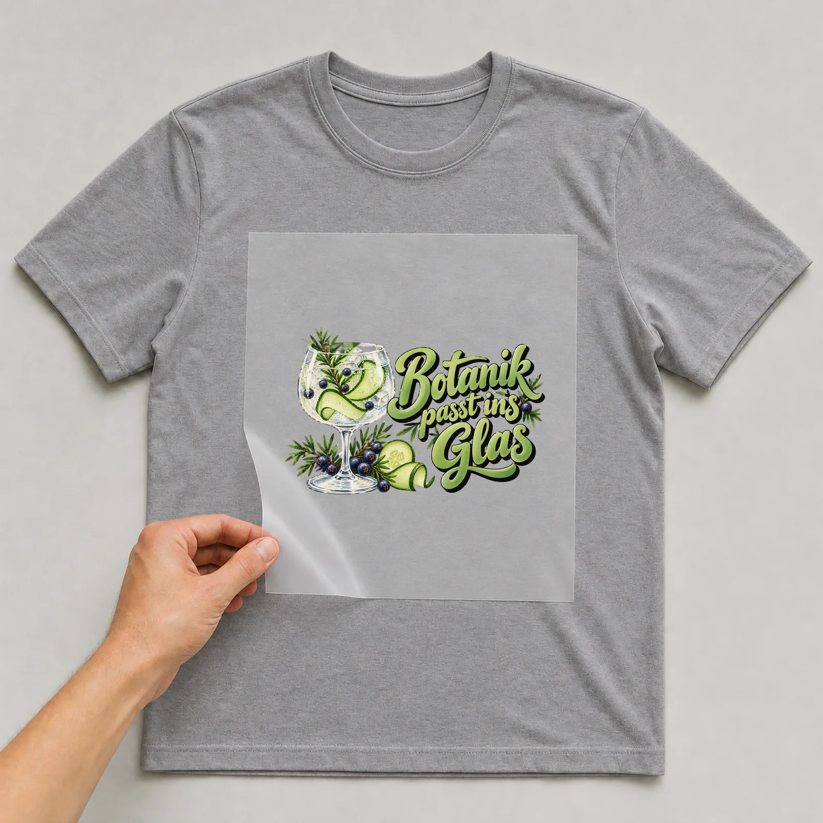 Bügelbild „Botanik passt ins Glas“ auf grauem T-Shirt, Folie wird aufgelegt