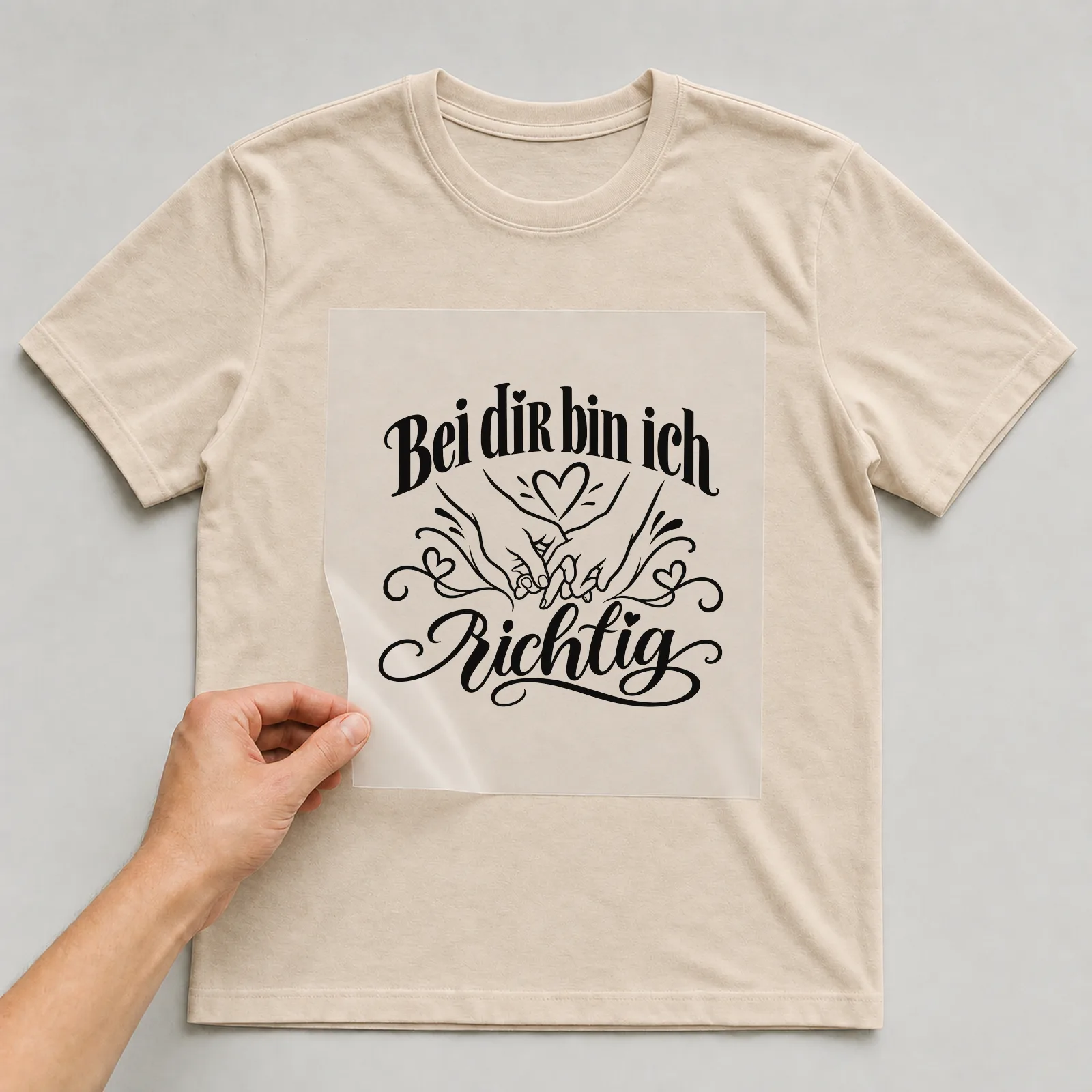 Bügelbild „Bei dir bin ich richtig“ auf beigem T-Shirt, Folie wird aufgelegt