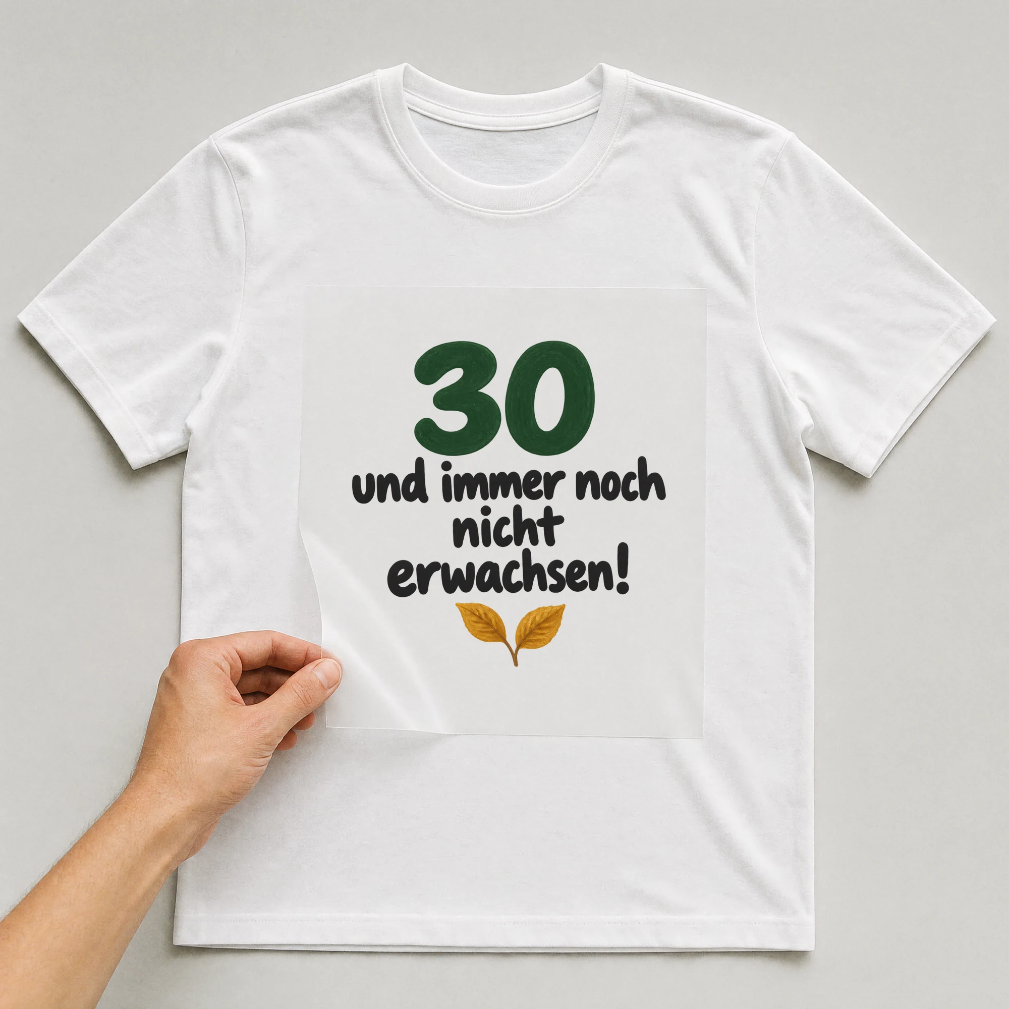 Bügelbild „30 und immer noch nicht erwachsen!“ auf weißem T-Shirt, Folie wird aufgelegt