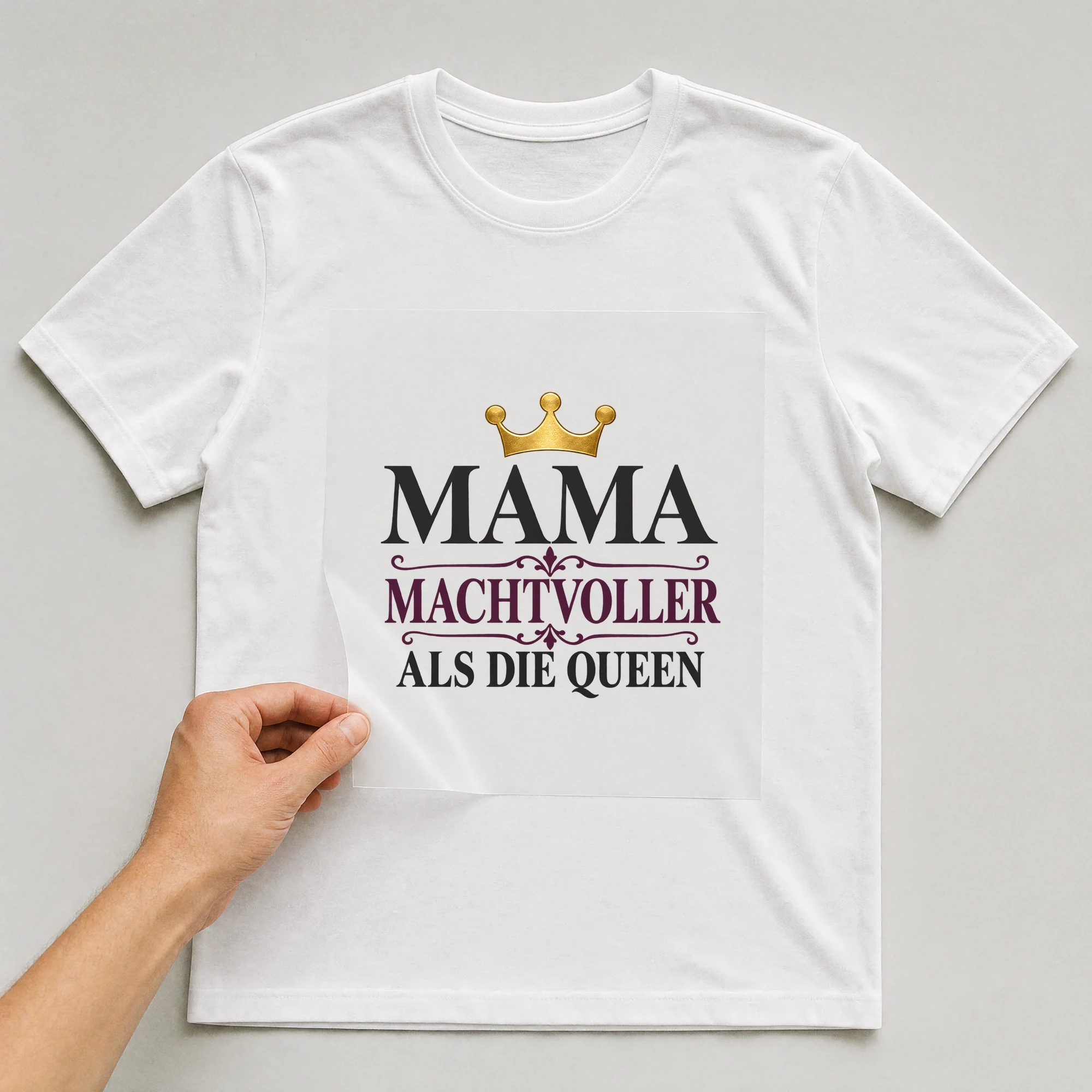 Bügelbild „Mama machtvoller als die Queen“ auf weißem T-Shirt, Folie wird aufgelegt