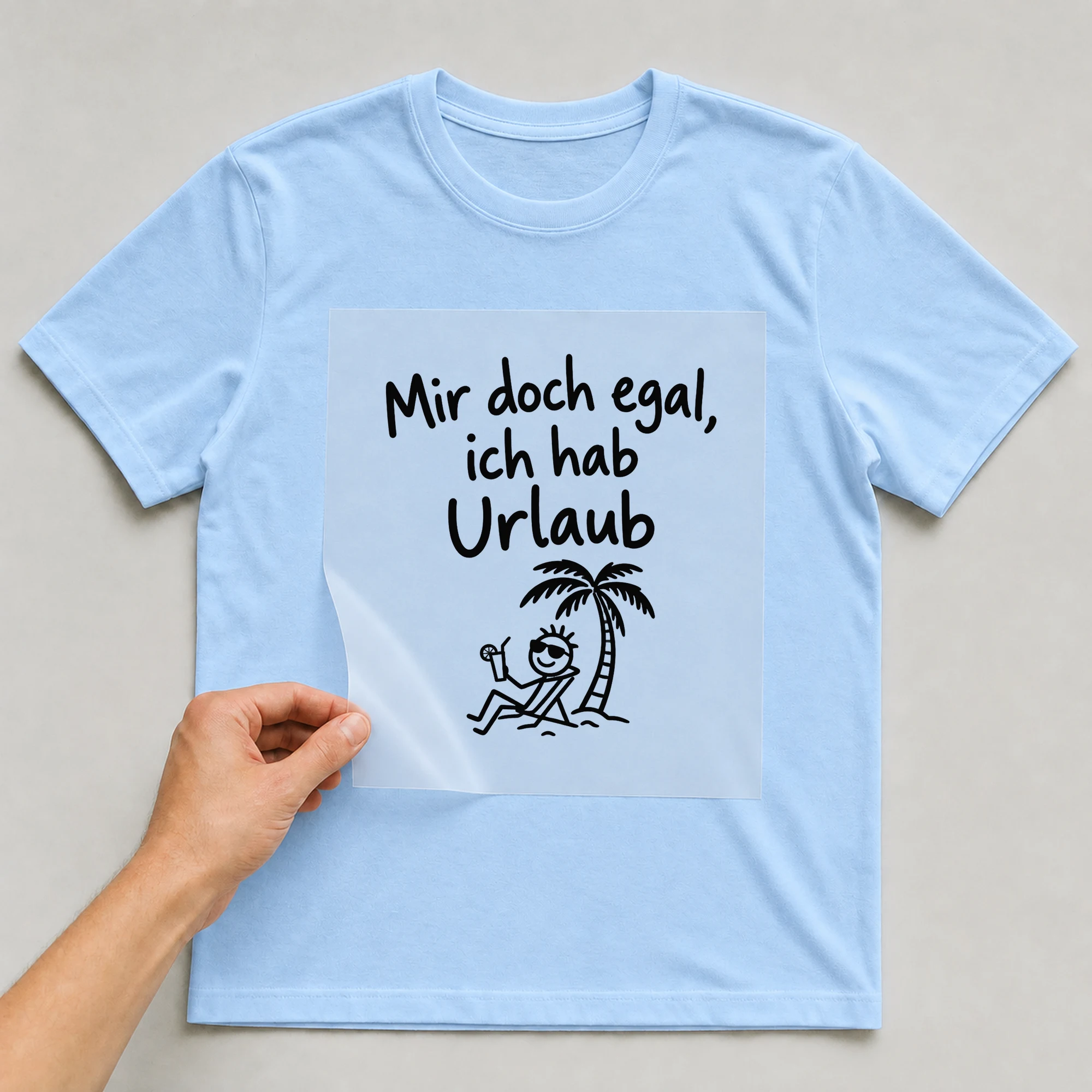 Bügelbild „Mir doch egal, ich hab Urlaub“ auf babyblauem T-Shirt, Folie wird aufgelegt