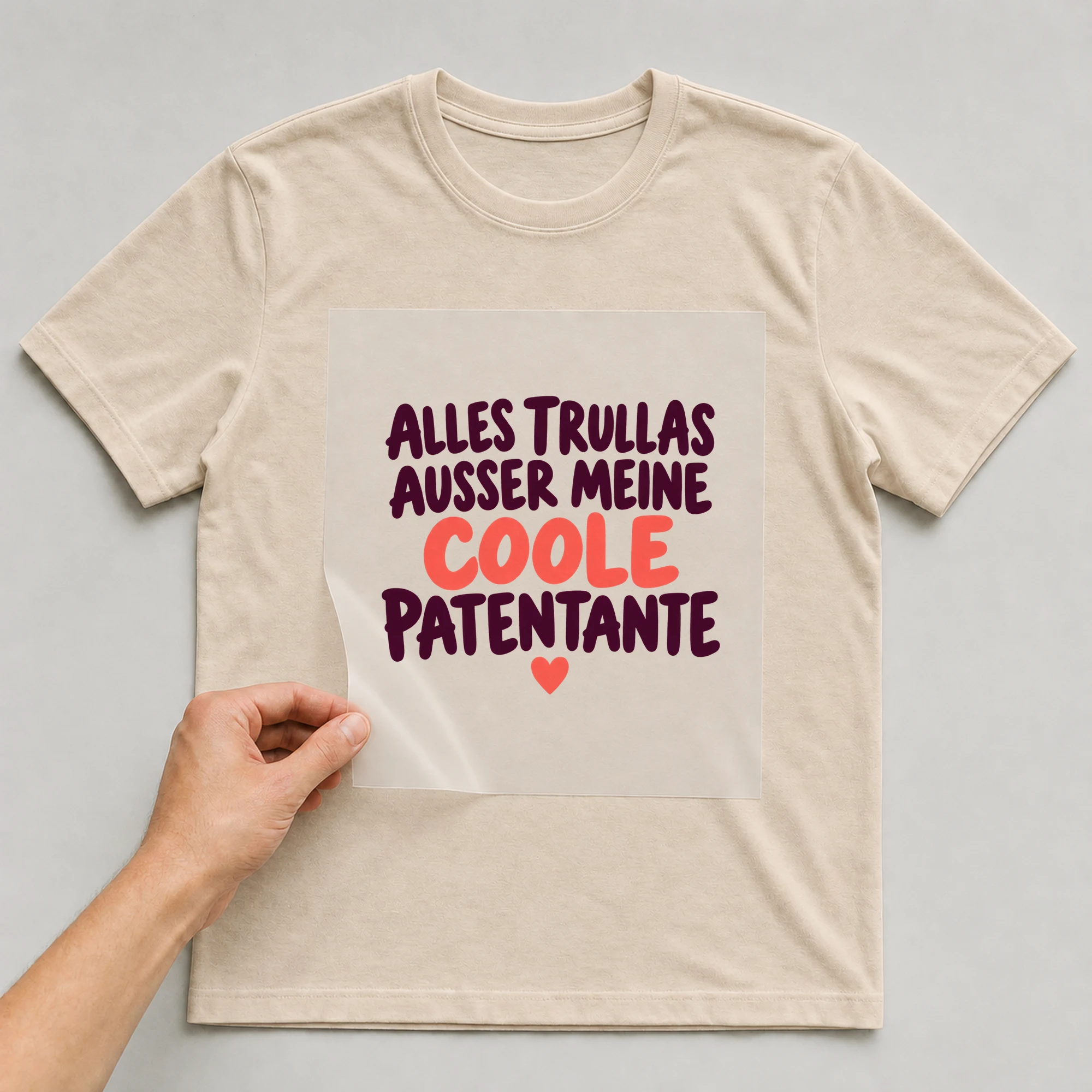 Bügelbild „Alles Trullas außer meine coole Patentante“ auf babyblauem T-Shirt, Folie wird aufgelegt