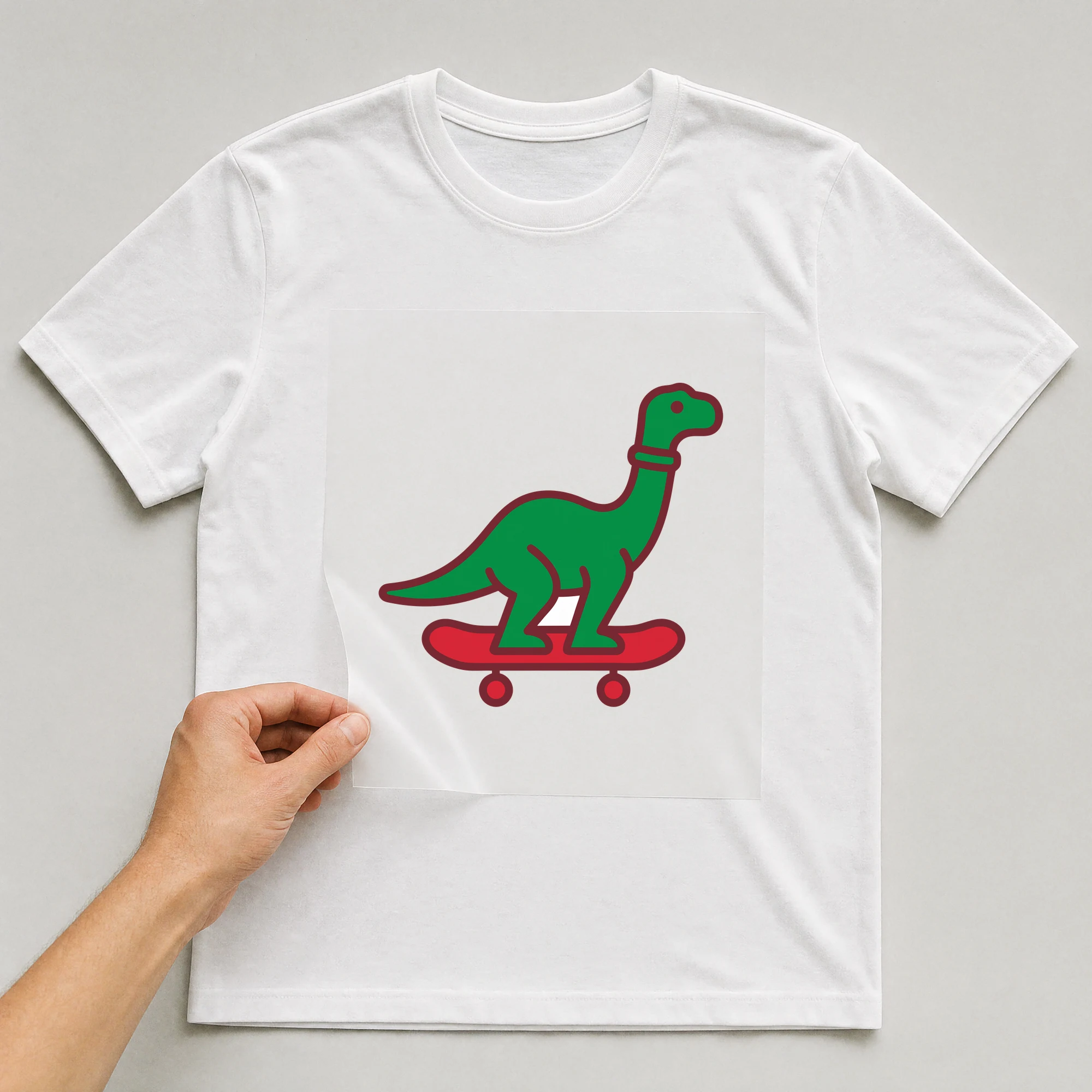 Bügelbild „Dino auf Skateboard“ auf weißem T-Shirt, Folie wird aufgelegt