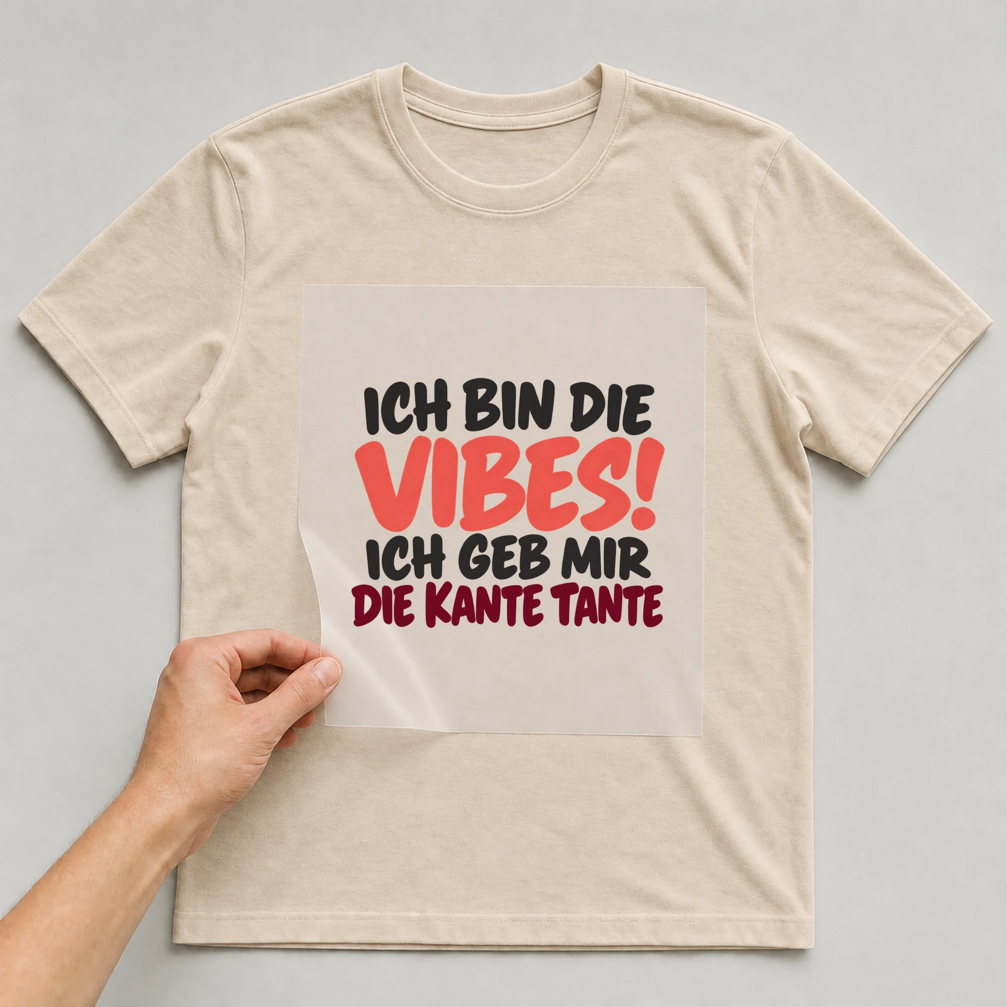 Bügelbild „Ich bin die vibes! Ich geb mir die Kante Tante“ auf beigem T-Shirt, Folie wird aufgelegt