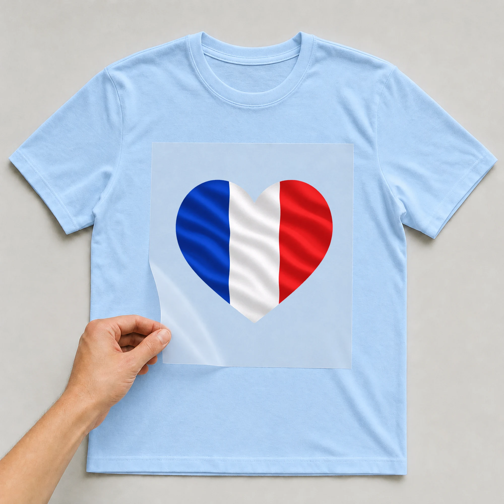 Bügelbild „Herz-Flagge Frankreich“ auf babyblauem T-Shirt, Folie wird aufgelegt