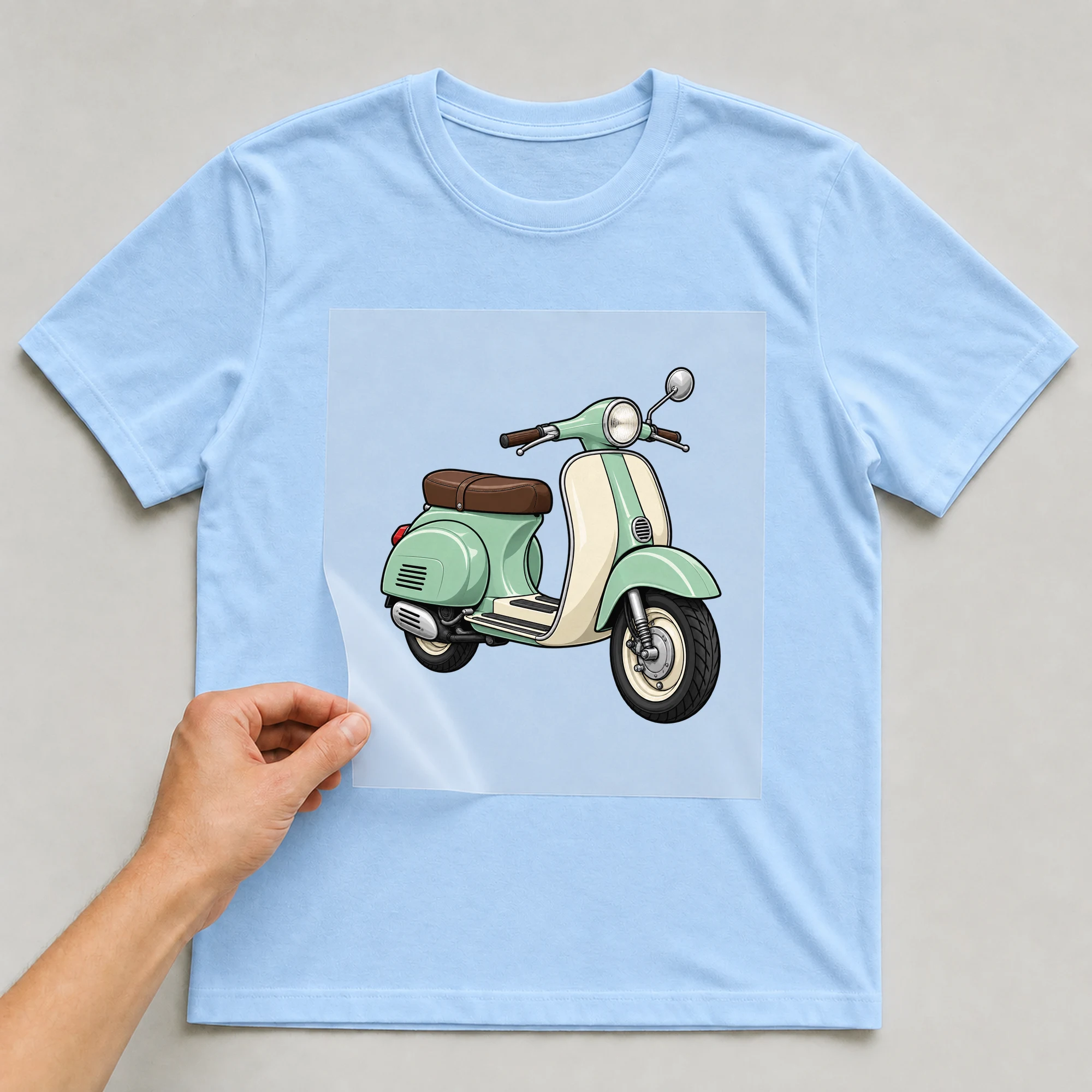 Bügelbild „Scooter Icon“ auf babyblauem T-Shirt, Folie wird aufgelegt