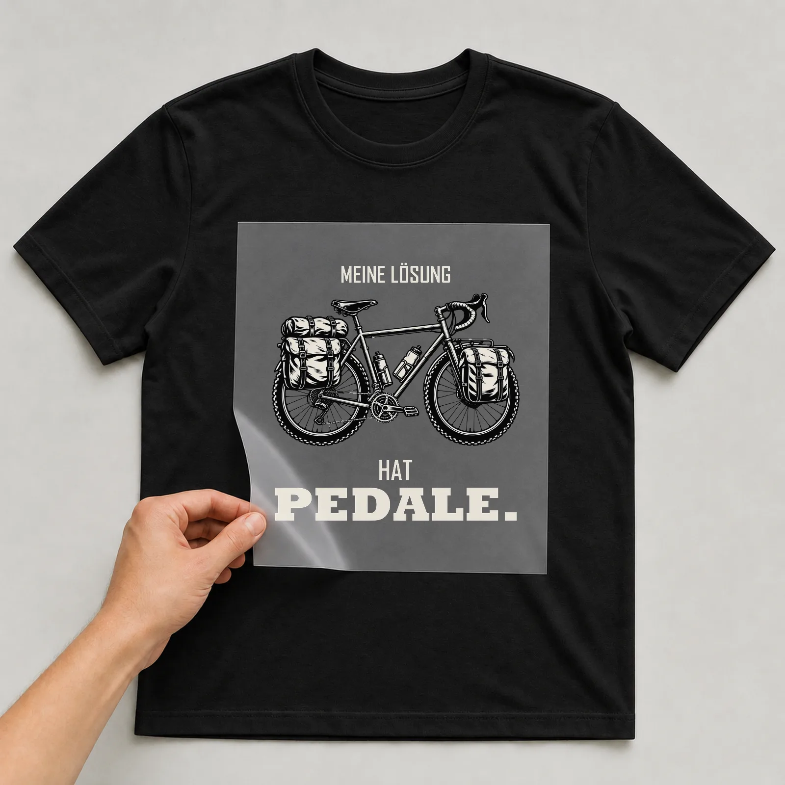 Bügelbild „Meine Lösung hat Pedale“ auf schwarzem T-Shirt, Folie wird aufgelegt