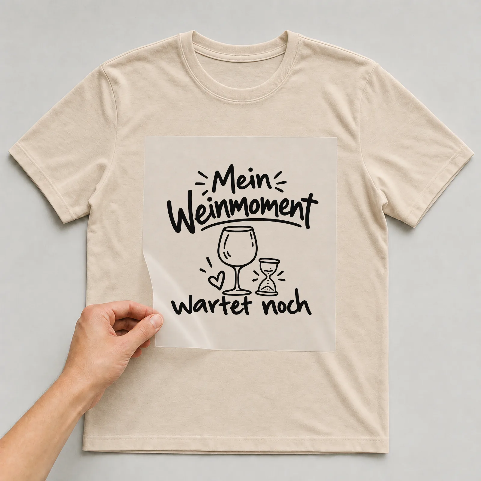 Bügelbild „Mein Weinmoment wartet noch“ auf beigem T-Shirt, Folie wird aufgelegt