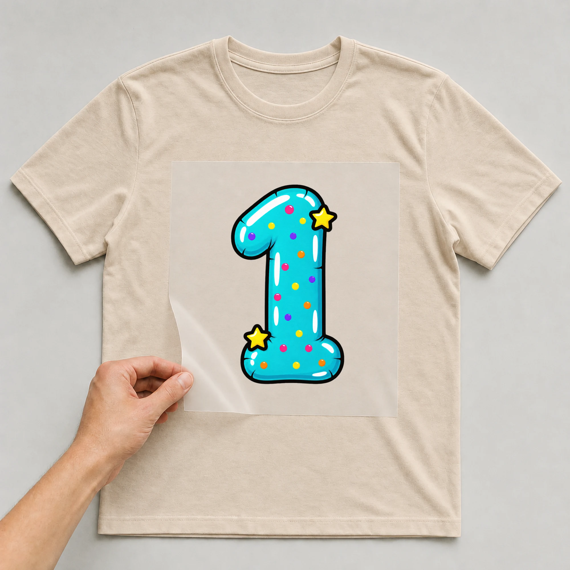 Bügelbild „Zahl 1 im Comic-Ballon-Stil“ auf beigem T-Shirt, Folie wird aufgelegt