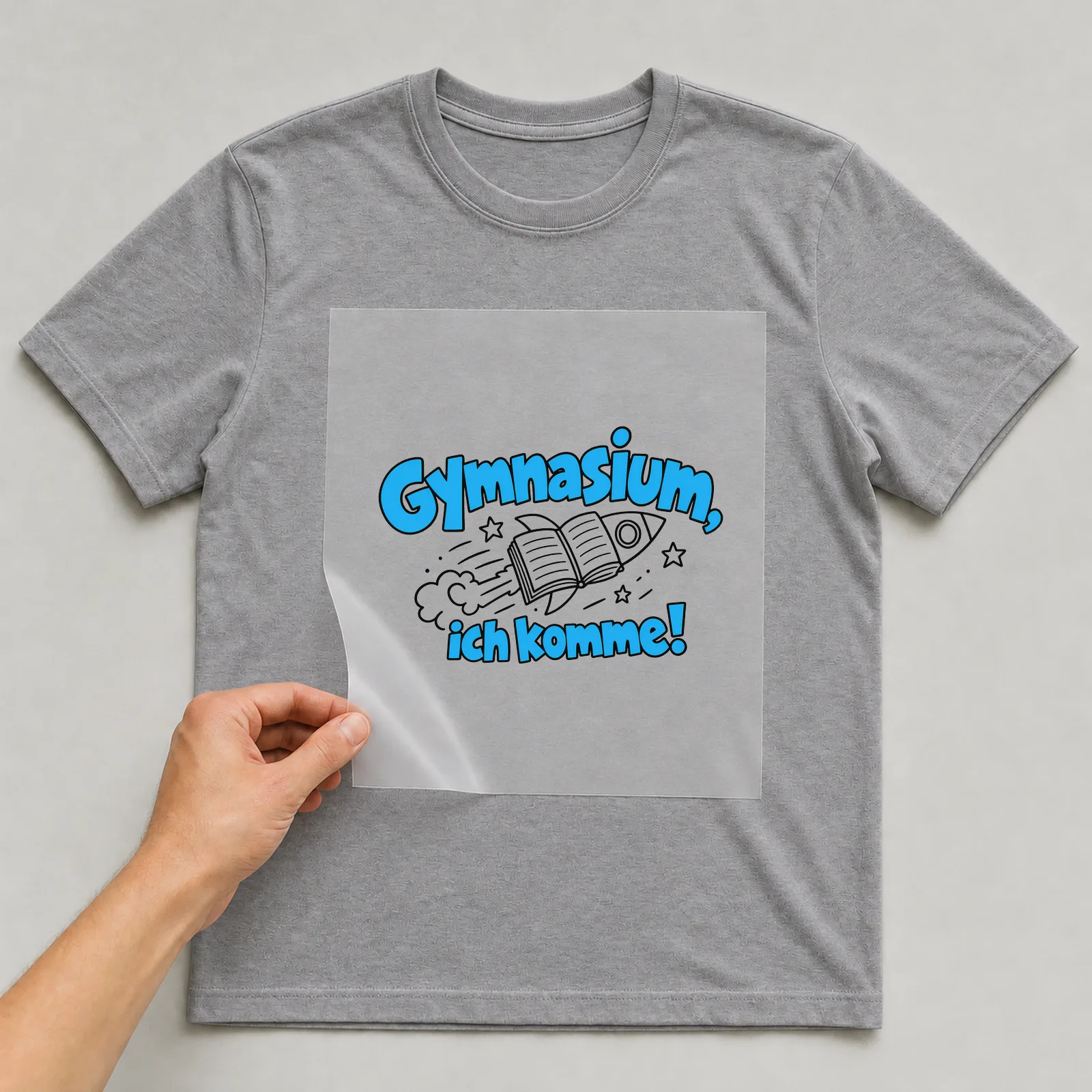 Bügelbild „Gymnasium, ich komme!“ auf grauem T-Shirt, Folie wird aufgelegt