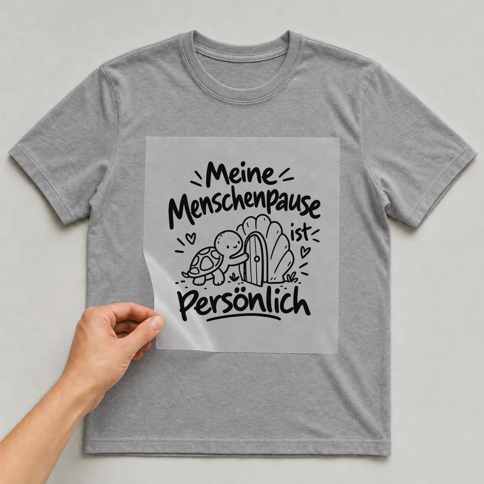 Bügelbild „Meine Menschenpause ist persönlich“ auf grauem T-Shirt, Folie wird aufgelegt