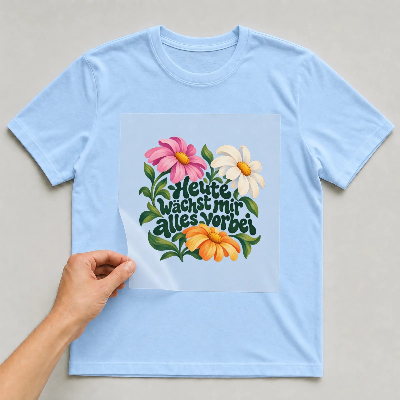Bügelbild „Heute wächst mir alles vorbei“ auf hellblauem T-Shirt, Folie wird aufgelegt