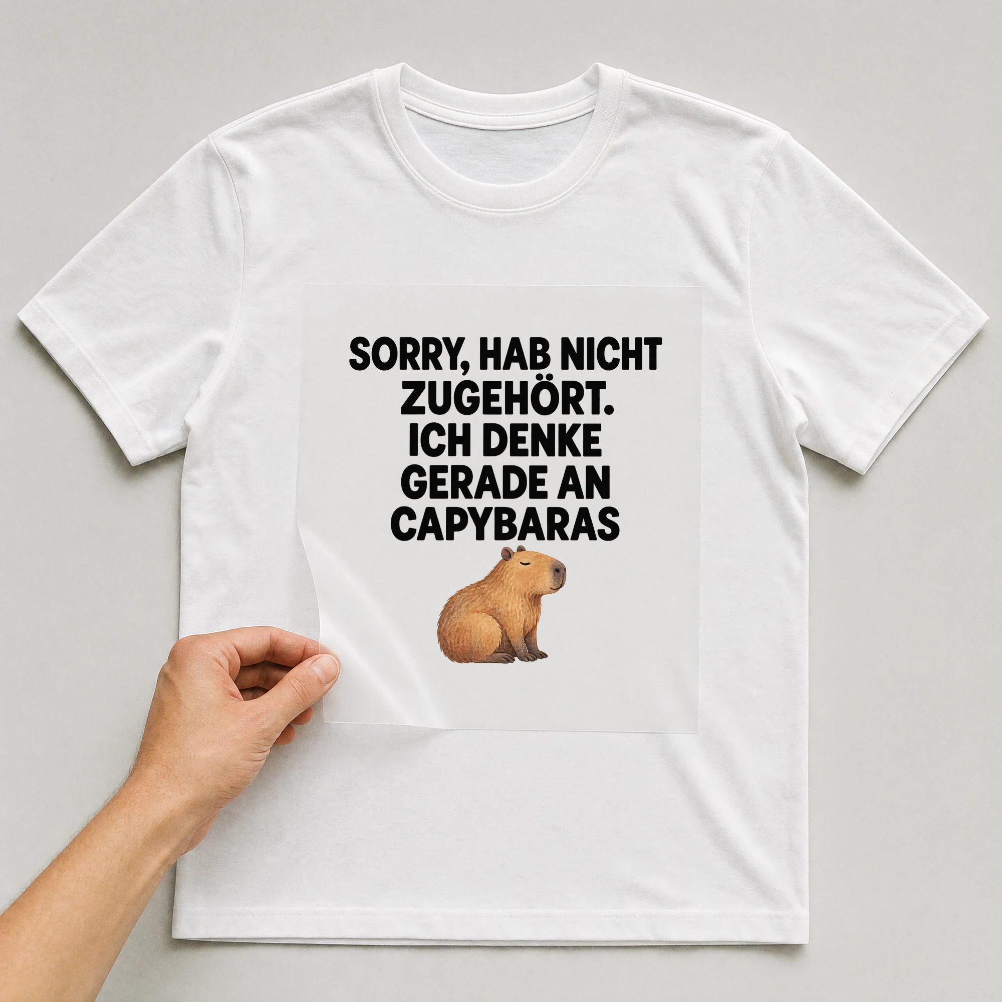 Bügelbild „Sorry, Hab Nicht Zugehört. Ich Denke Gerade An Capybaras“ auf weißem T-Shirt, Folie wird aufgelegt