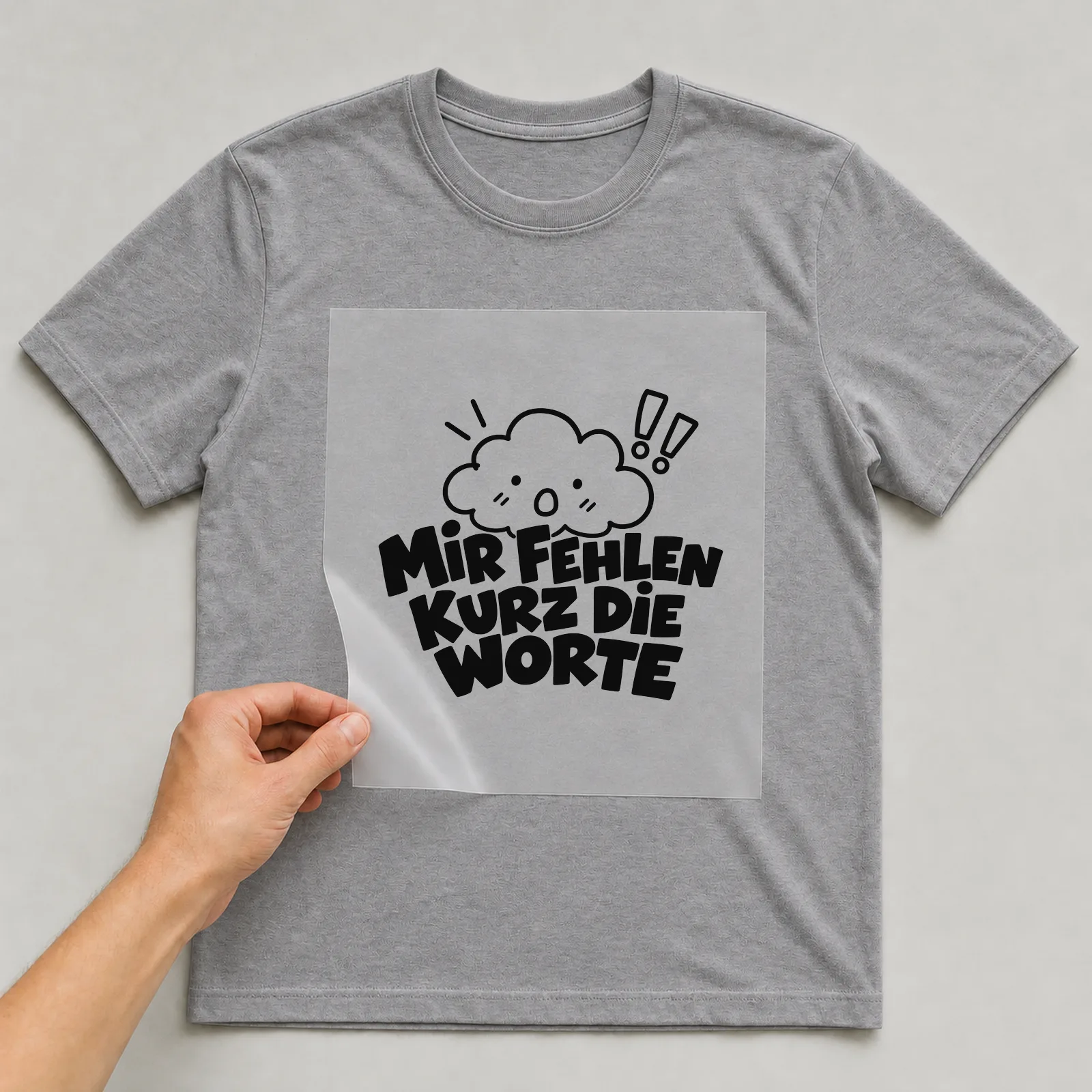 Bügelbild „Mir fehlen kurz die Worte“ auf grauem T-Shirt, Folie wird aufgelegt