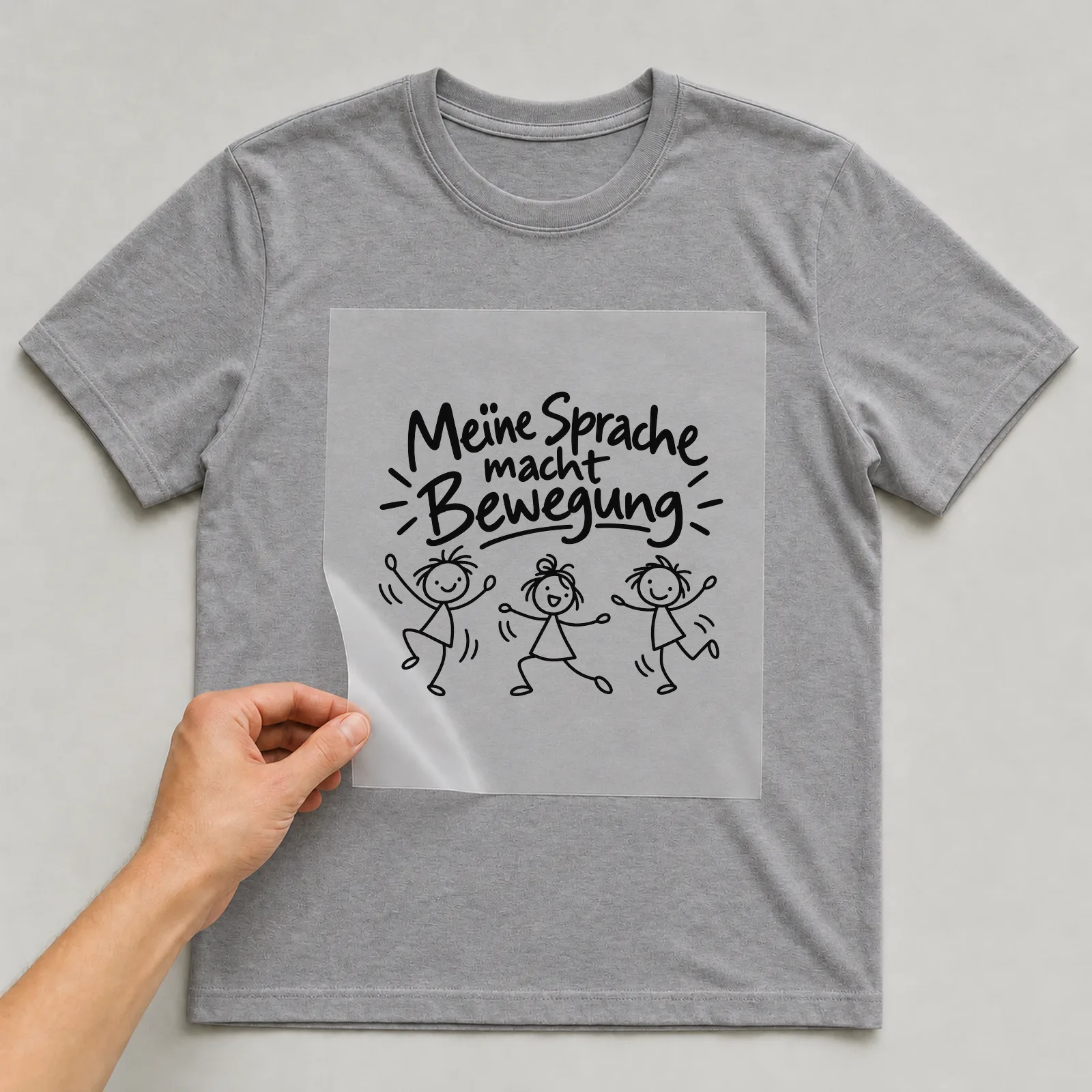 Bügelbild „Meine Sprache macht Bewegung“ auf grauem T-Shirt, Folie wird aufgelegt