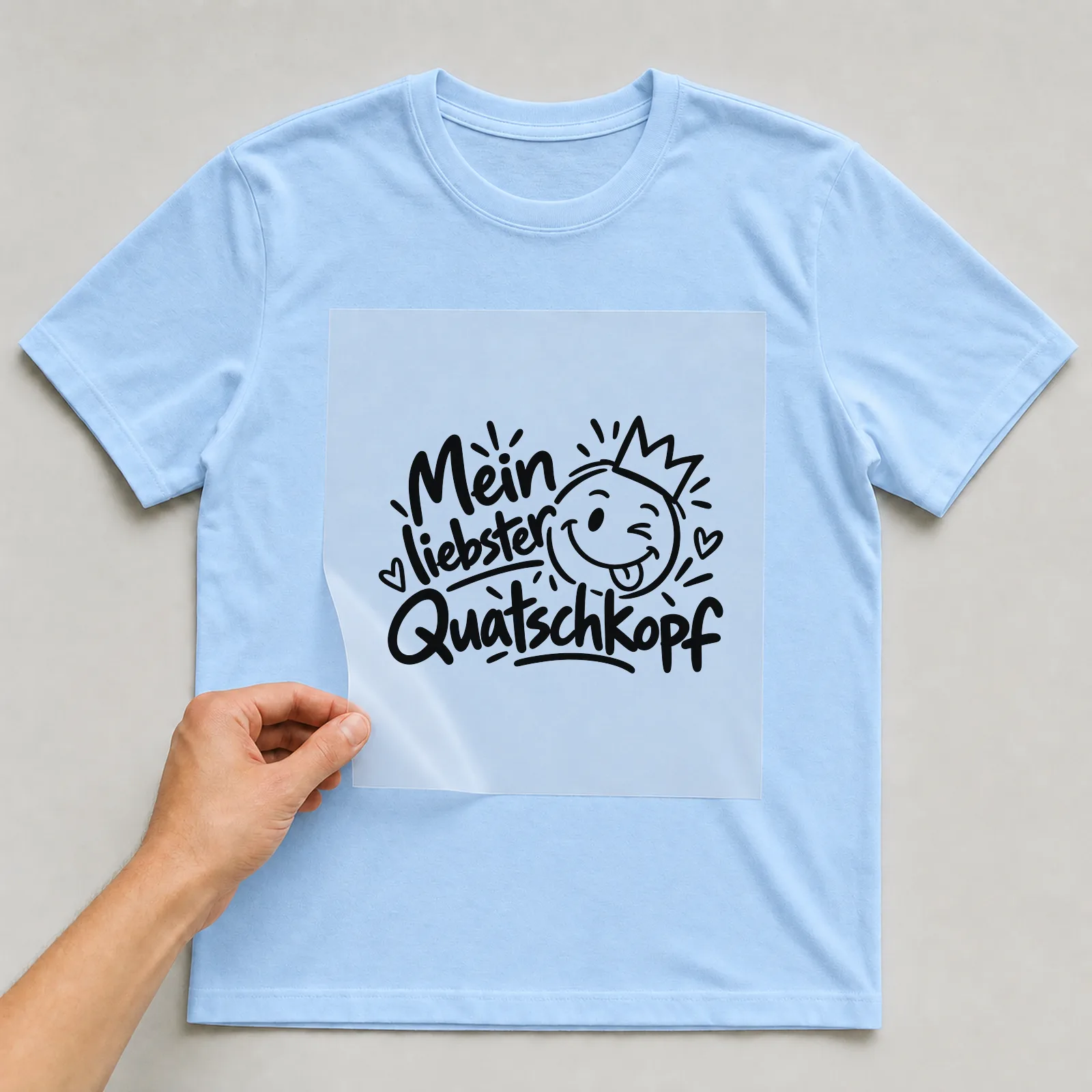 Bügelbild „Mein liebster Quatschkopf“ auf hellblauem T-Shirt, Folie wird aufgelegt