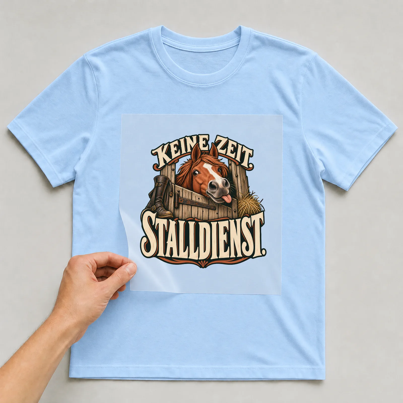 Bügelbild „Keine Zeit. Stalldienst.“ auf hellblauem T-Shirt, Folie wird aufgelegt