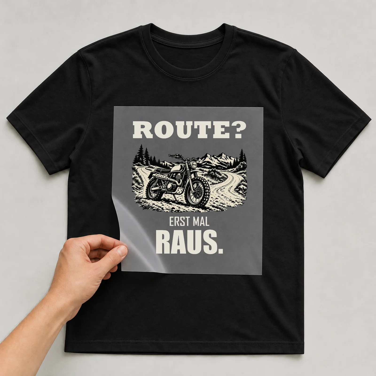 Bügelbild „Route? Erst mal raus.“ auf schwarzem T-Shirt, Folie wird aufgelegt