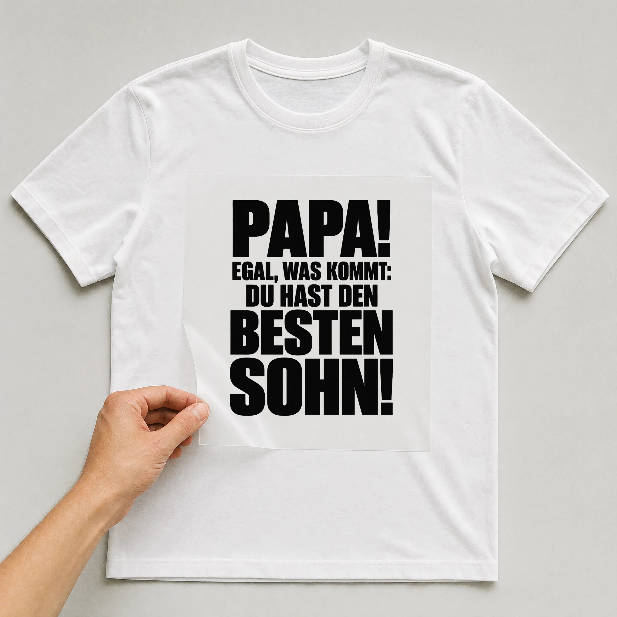 Bügelbild „Papa! Egal, was kommt: Du hast den besten Sohn!“ auf weißem T-Shirt, Folie wird aufgelegt