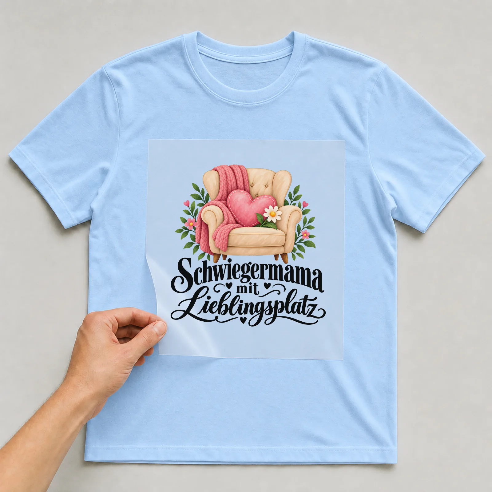 Bügelbild „Schwiegermama mit Lieblingsplatz“ auf hellblauem T-Shirt, Folie wird aufgelegt