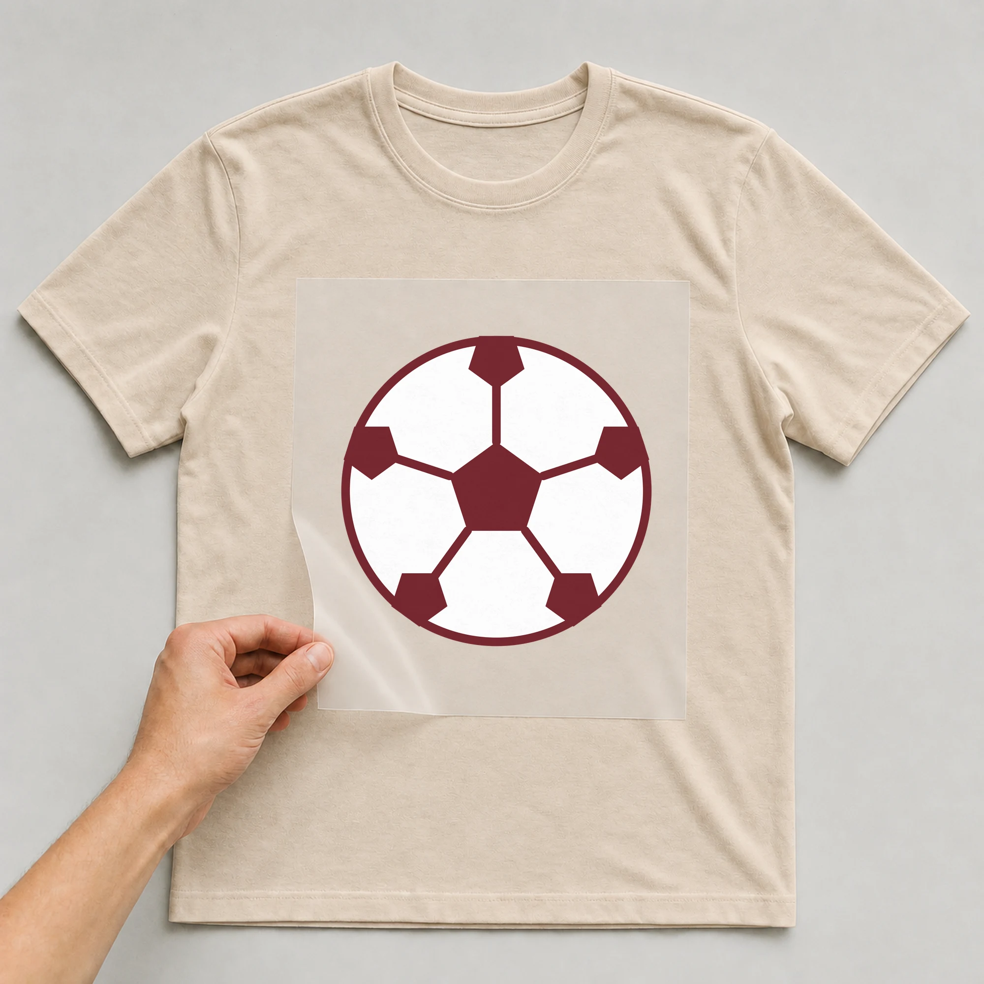 Bügelbild „Fußball klein“ auf beigem T-Shirt, Folie wird aufgelegt