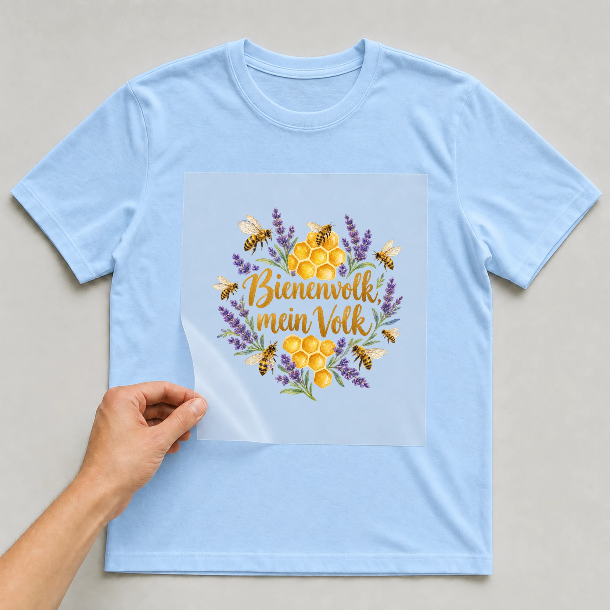 Bügelbild „Bienenvolk, mein Volk“ auf babyblauem T-Shirt, Folie wird aufgelegt