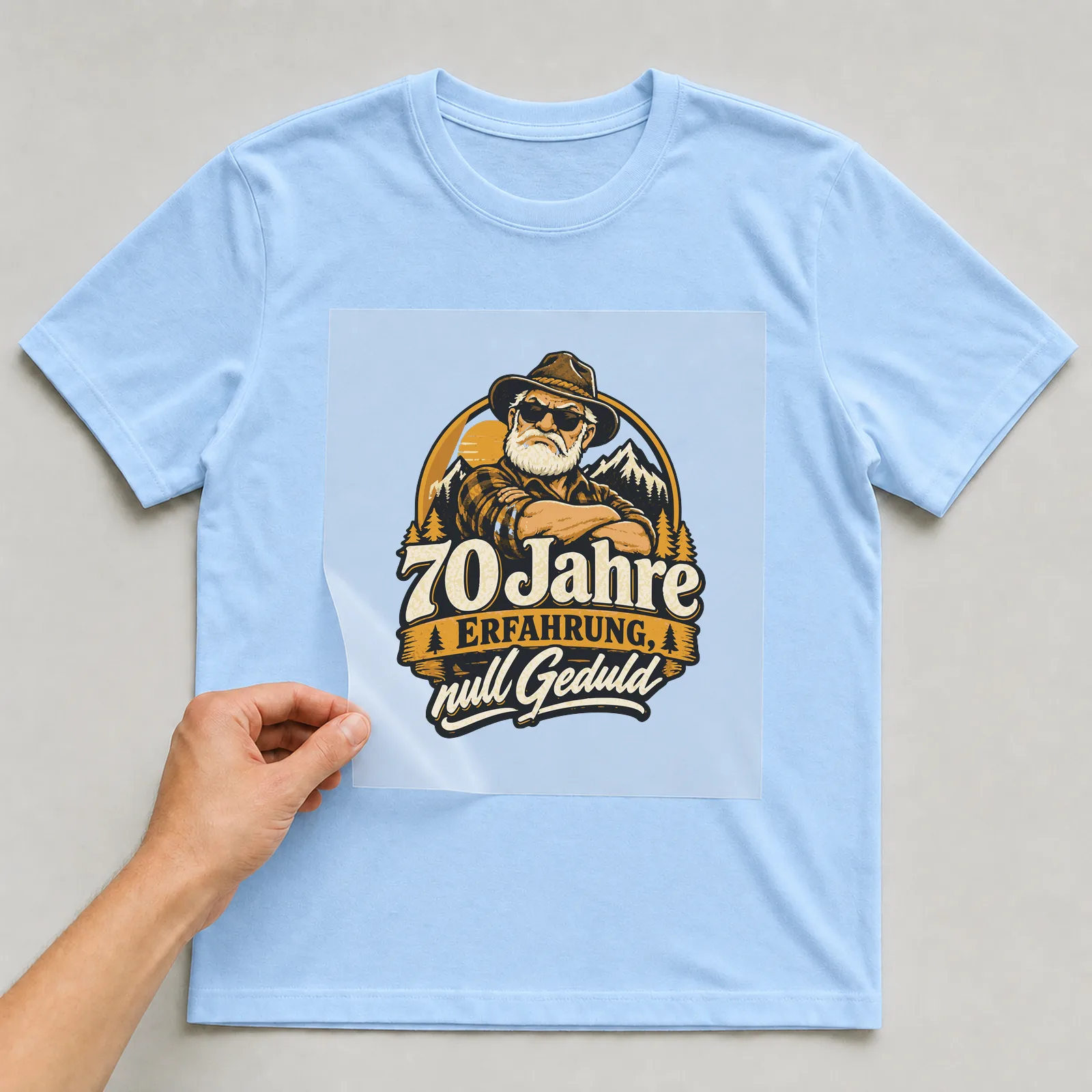 Bügelbild 70 Jahre Erfahrung, null Geduld auf hellblauem T-Shirt, Folie wird aufgelegt