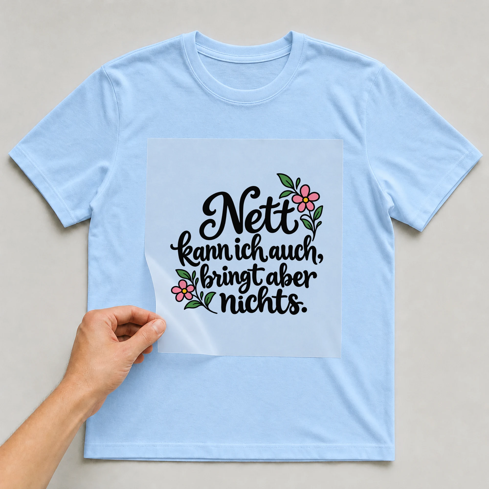 Bügelbild „Nett kann ich auch, bringt aber nichts.“ auf babyblauem T-Shirt, Folie wird aufgelegt