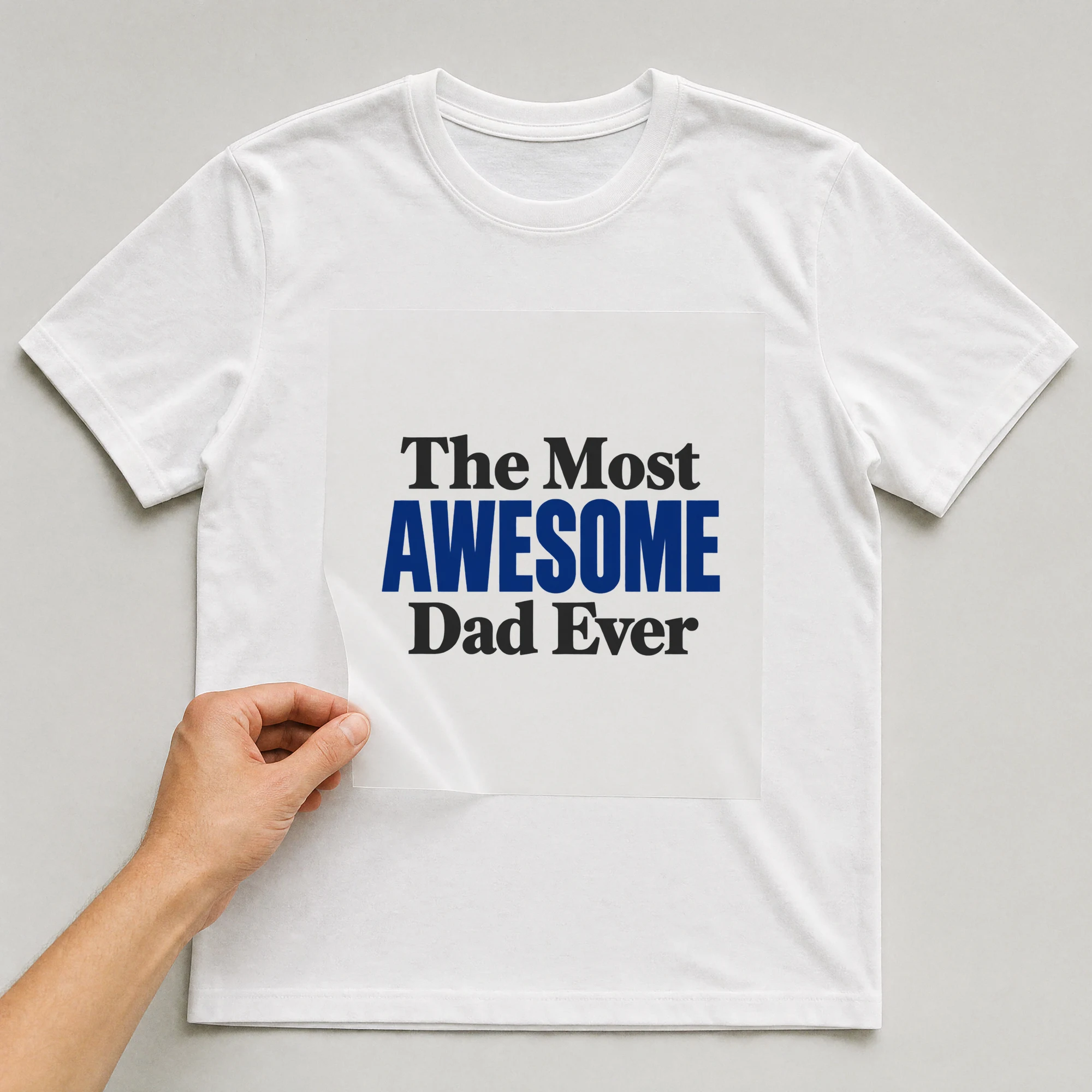 Bügelbild „The Most AWESOME Dad Ever“ auf weißem T-Shirt, Folie wird aufgelegt