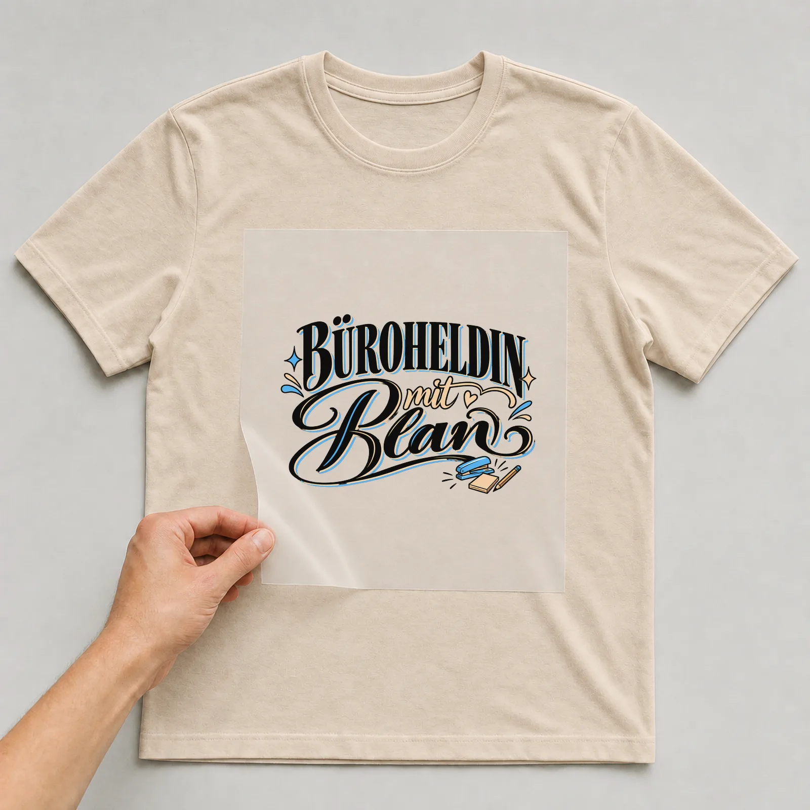 Bügelbild „Büroheldin mit Plan“ auf beigem T-Shirt, Folie wird aufgelegt