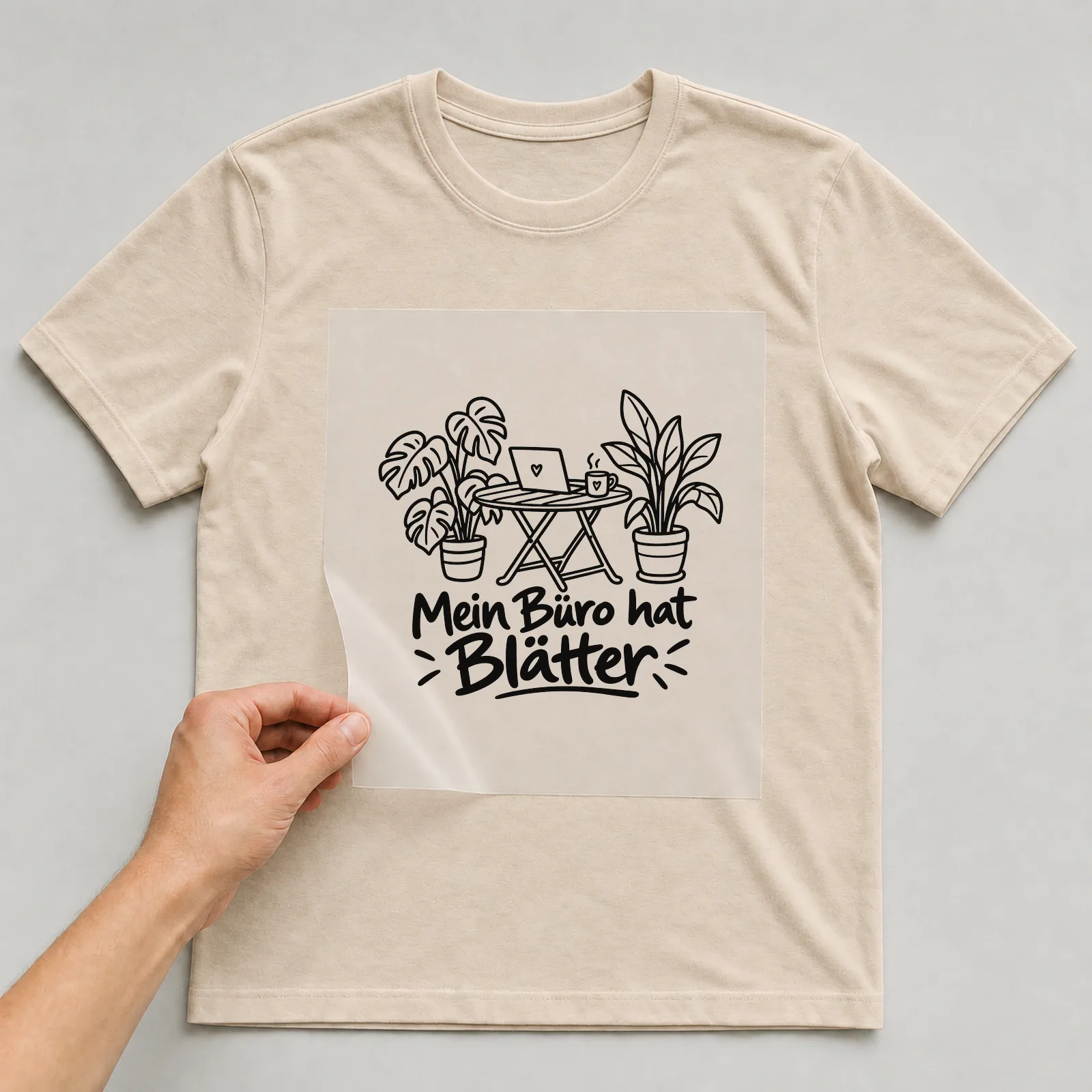 Bügelbild „Mein Büro hat Blätter“ auf beigem T-Shirt, Folie wird aufgelegt