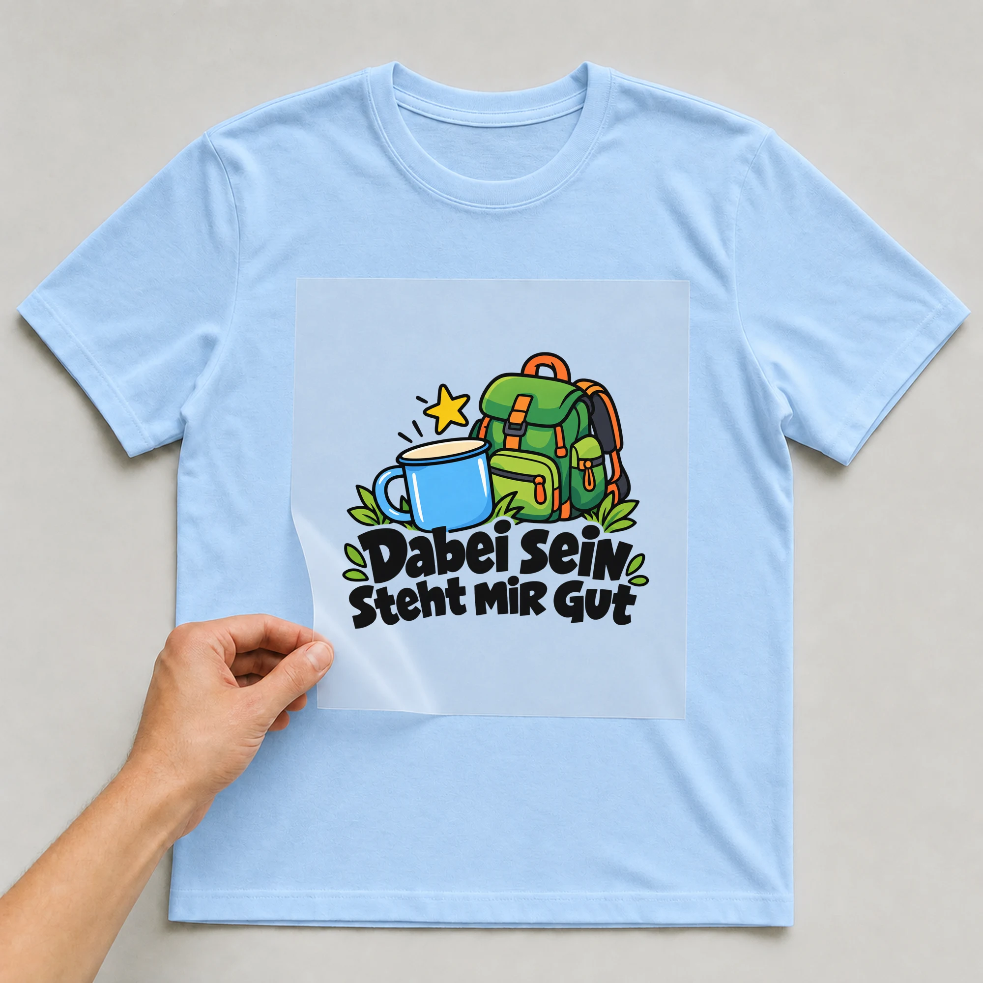 Bügelbild „Dabei sein steht mir gut“ auf babyblauem T-Shirt, Folie wird aufgelegt