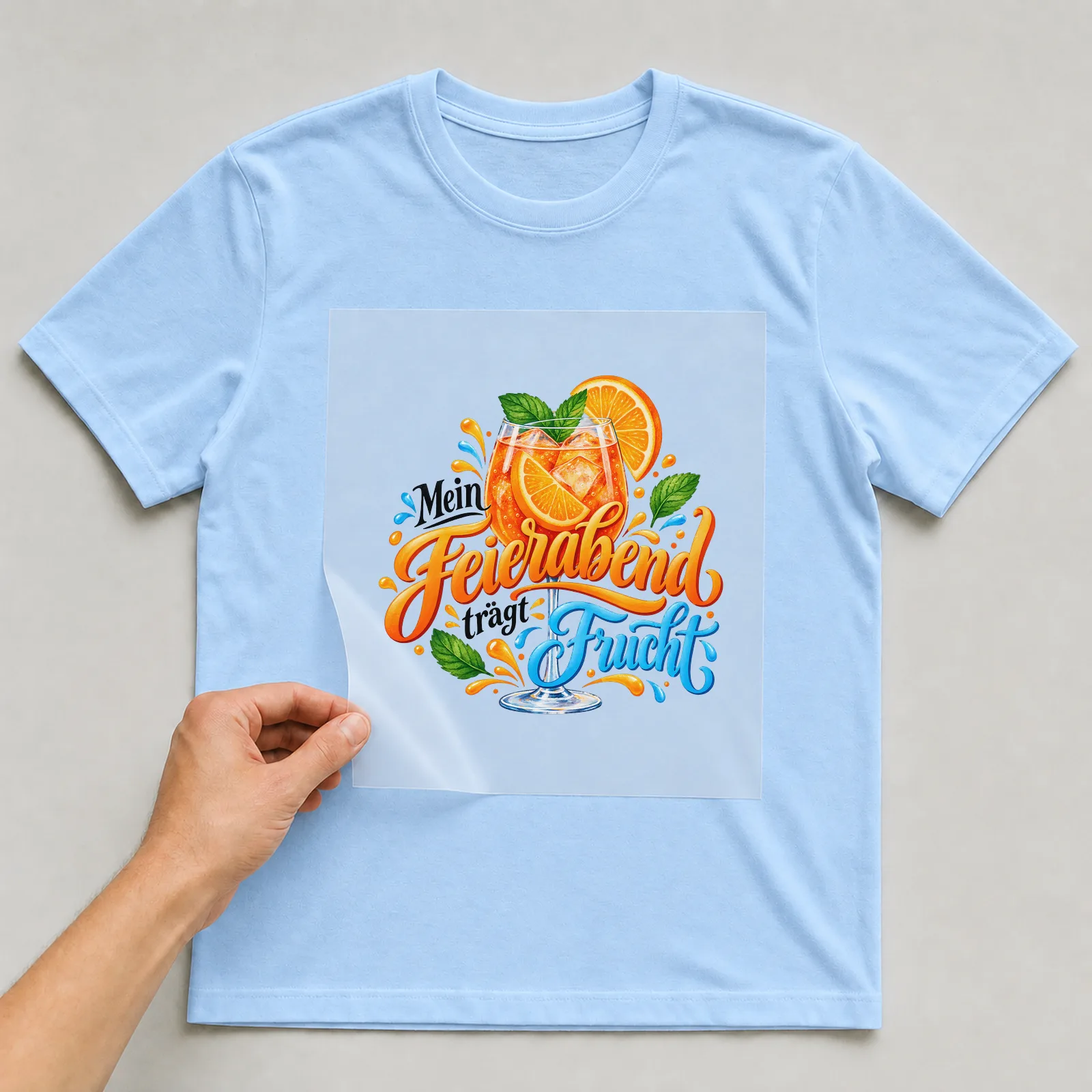 Bügelbild „Mein Feierabend trägt Frucht“ auf hellblauem T-Shirt, Folie wird aufgelegt