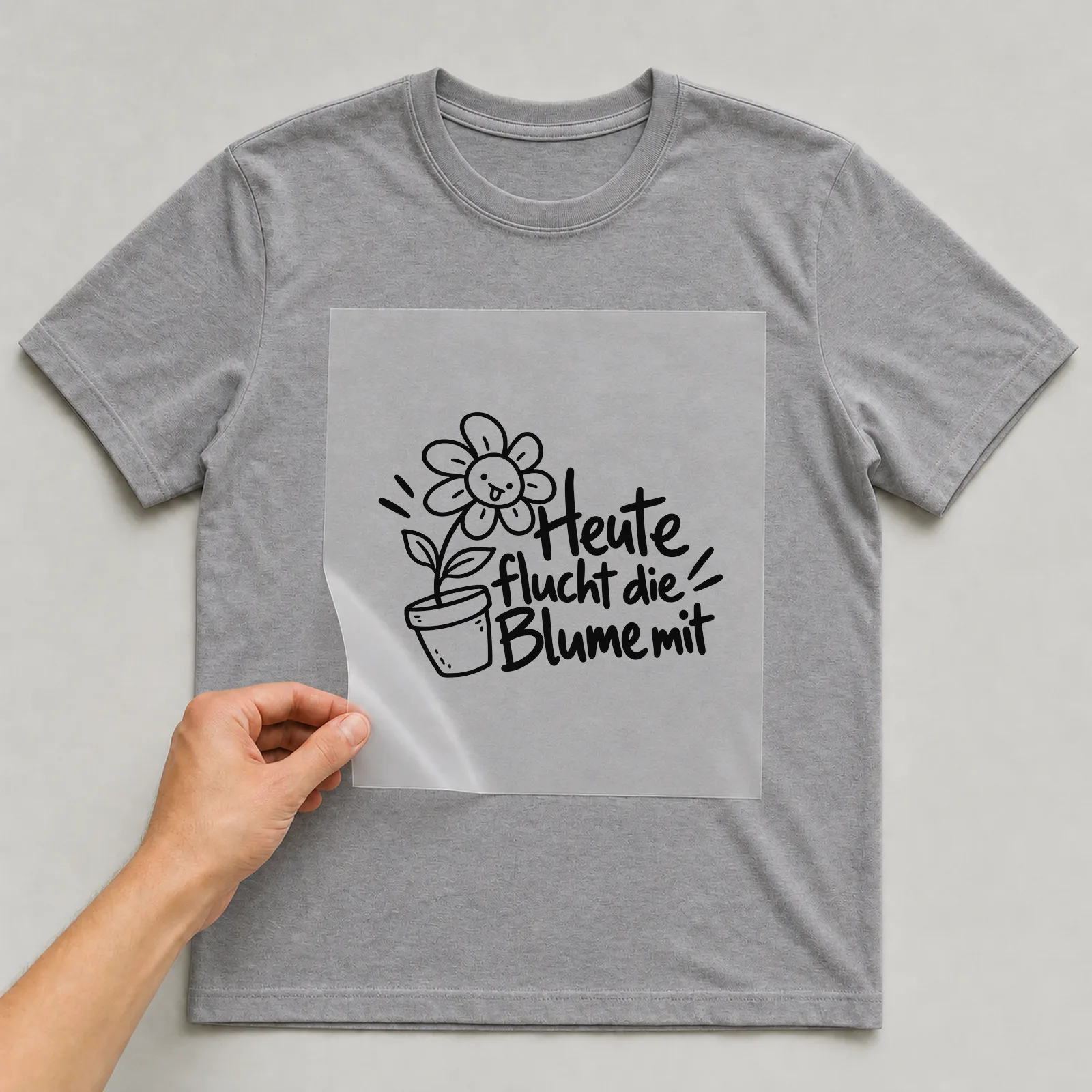 Bügelbild „Heute flucht die Blume mit“ auf grauem T-Shirt, Folie wird aufgelegt