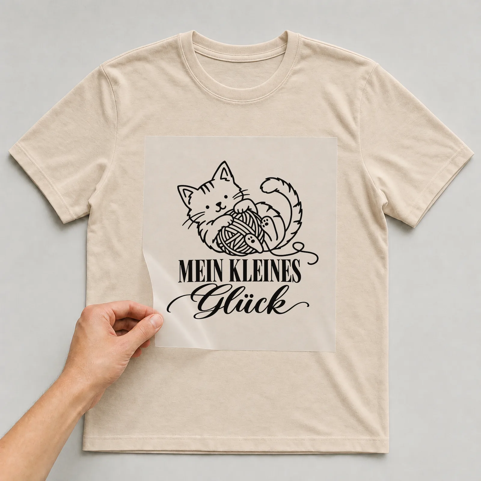 Bügelbild „Mein kleines Glück“ auf beigem T-Shirt, Folie wird aufgelegt
