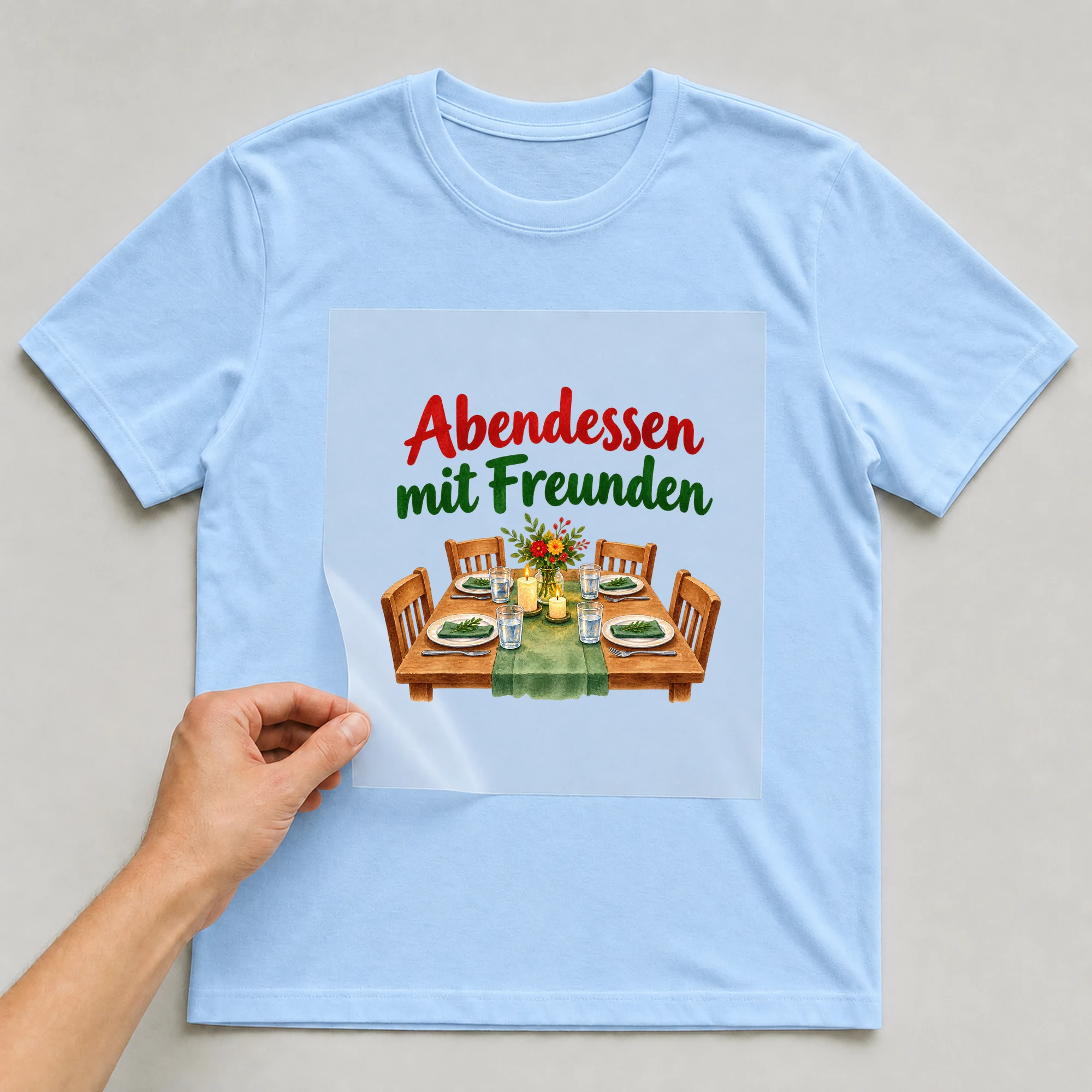 Bügelbild „Abendessen mit Freunden“ auf babyblauem T-Shirt, Folie wird aufgelegt