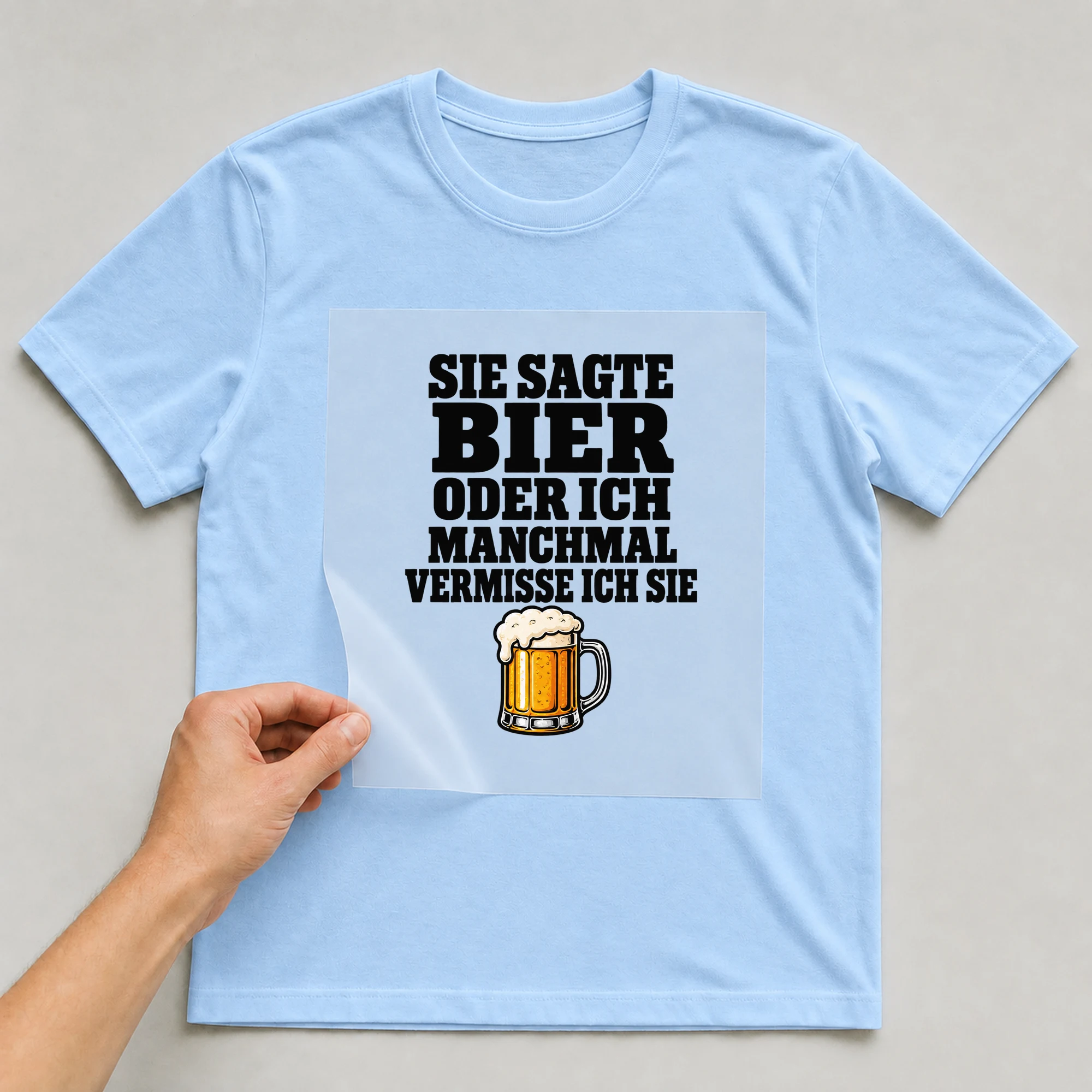 Bügelbild „Sie sagte Bier oder ich manchmal vermisse ich sie“ auf babyblauem T-Shirt, Folie wird aufgelegt