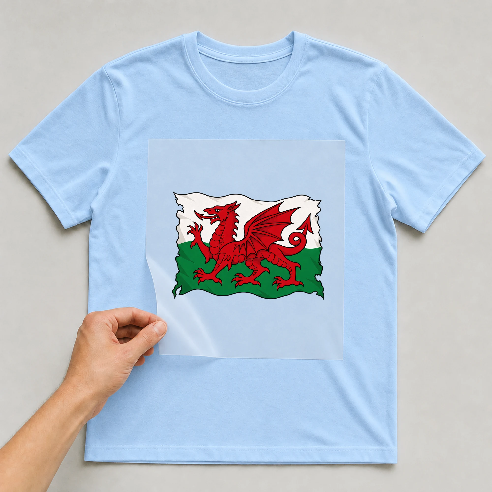 Bügelbild „Zerrissene Fahne Wales“ auf babyblauem T-Shirt, Folie wird aufgelegt