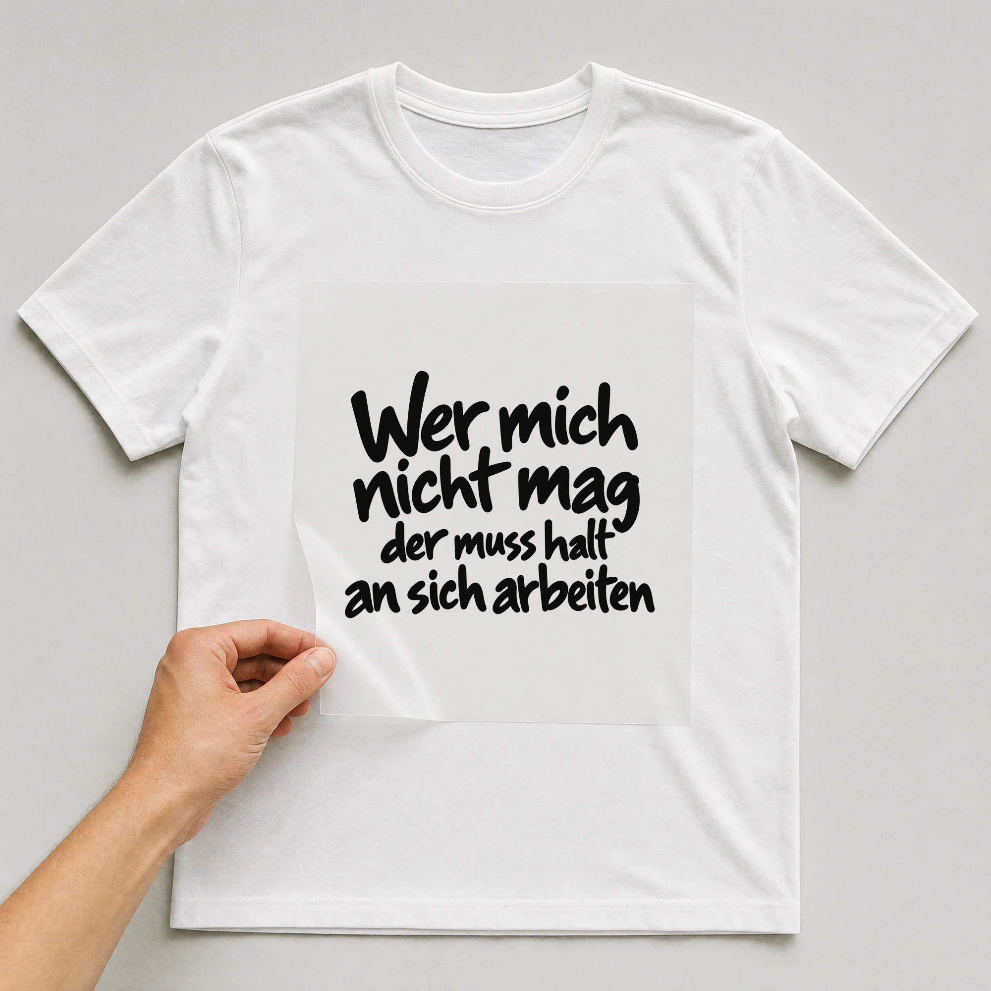 Bügelbild „Wer mich nicht mag der muss halt an sich arbeiten“ auf weißem T-Shirt, Folie wird aufgelegt