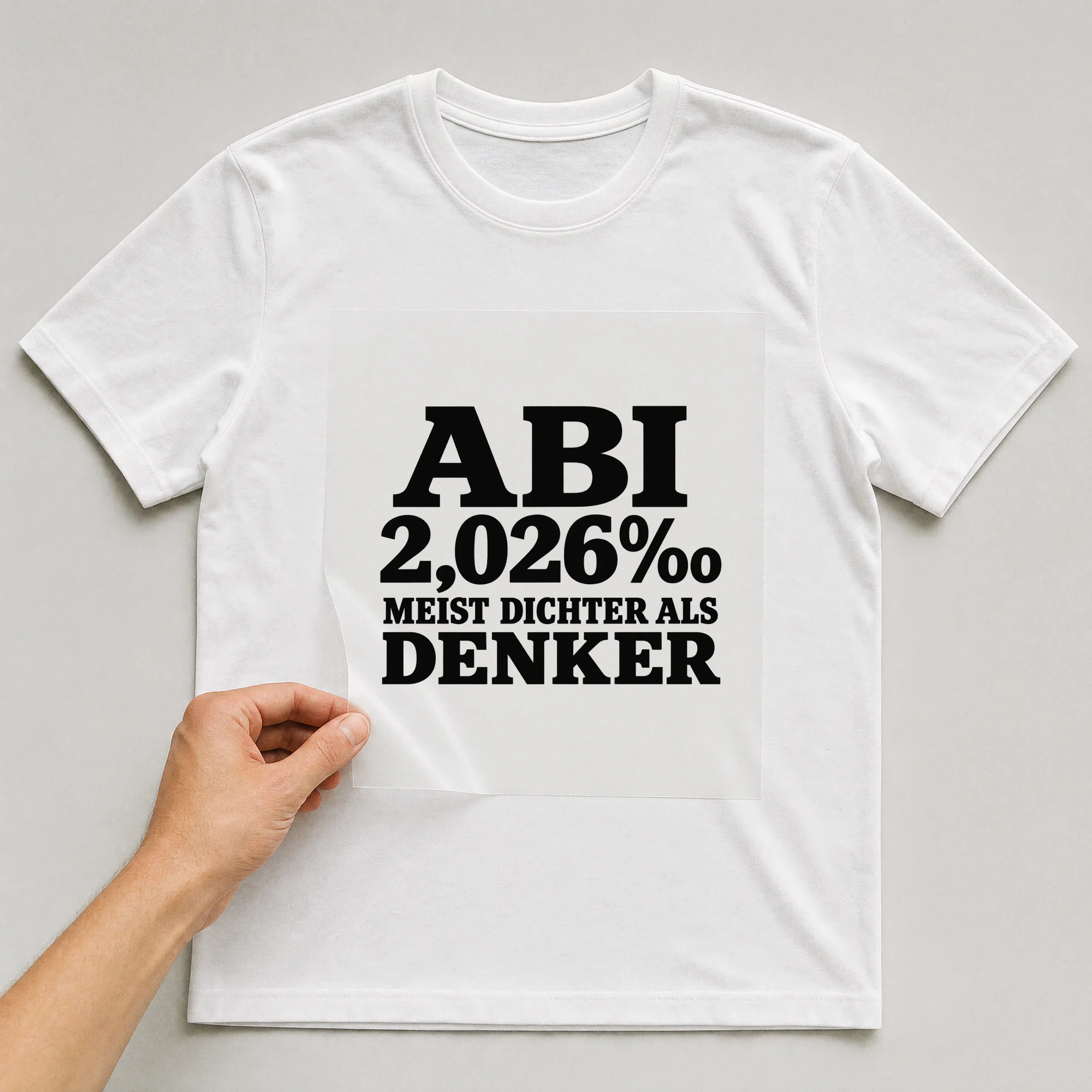 Bügelbild „Abi 2,026‰ meist Dichter als Denker“ auf weißem T-Shirt, Folie wird aufgelegt