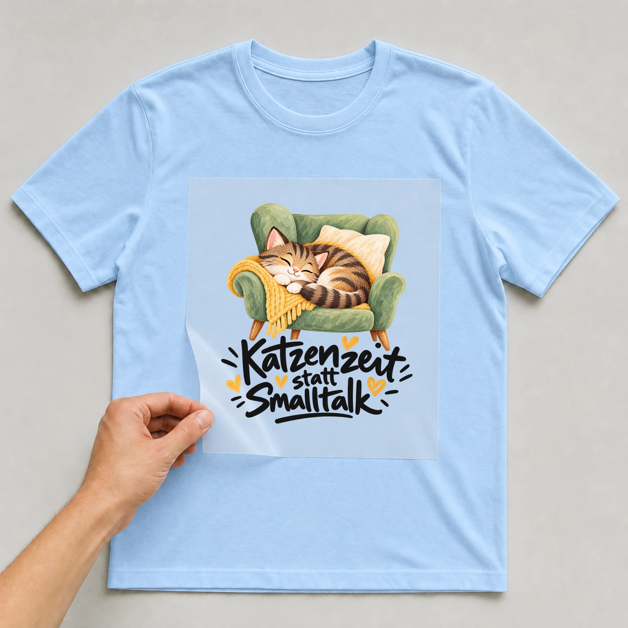 Bügelbild „Katzenzeit statt Smalltalk“ auf hellblauem T-Shirt, Folie wird aufgelegt