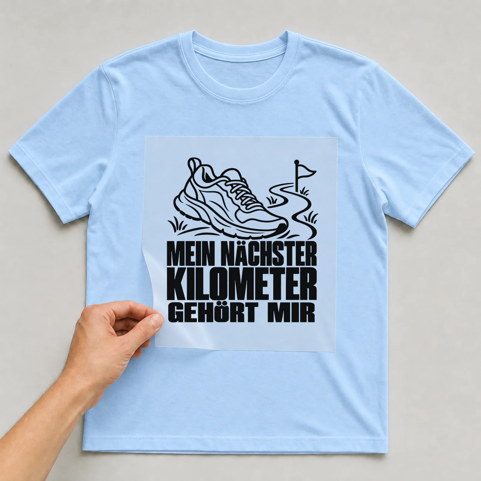 Bügelbild „Mein nächster Kilometer gehört mir“ auf hellblauem T-Shirt, Folie wird aufgelegt