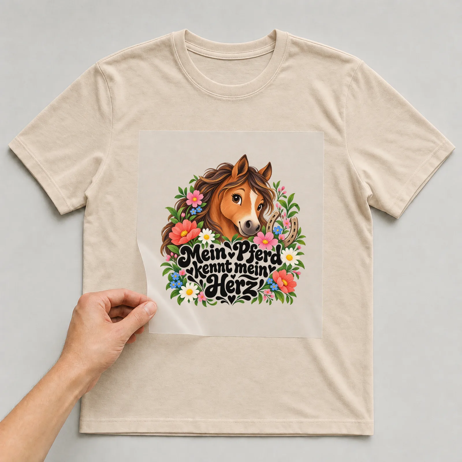 Bügelbild „Mein Pferd kennt mein Herz“ auf beigem T-Shirt, Folie wird aufgelegt