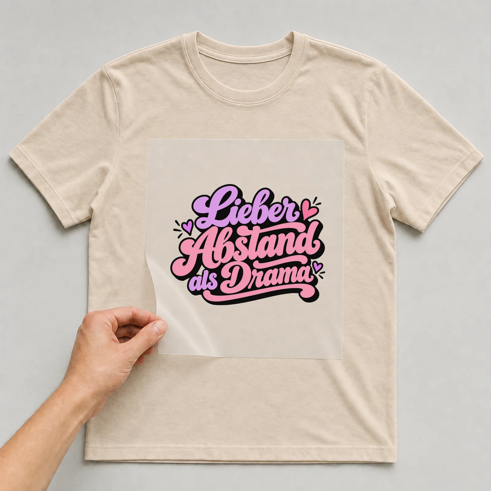 Bügelbild „Lieber Abstand als Drama“ auf beigem T-Shirt, Folie wird aufgelegt