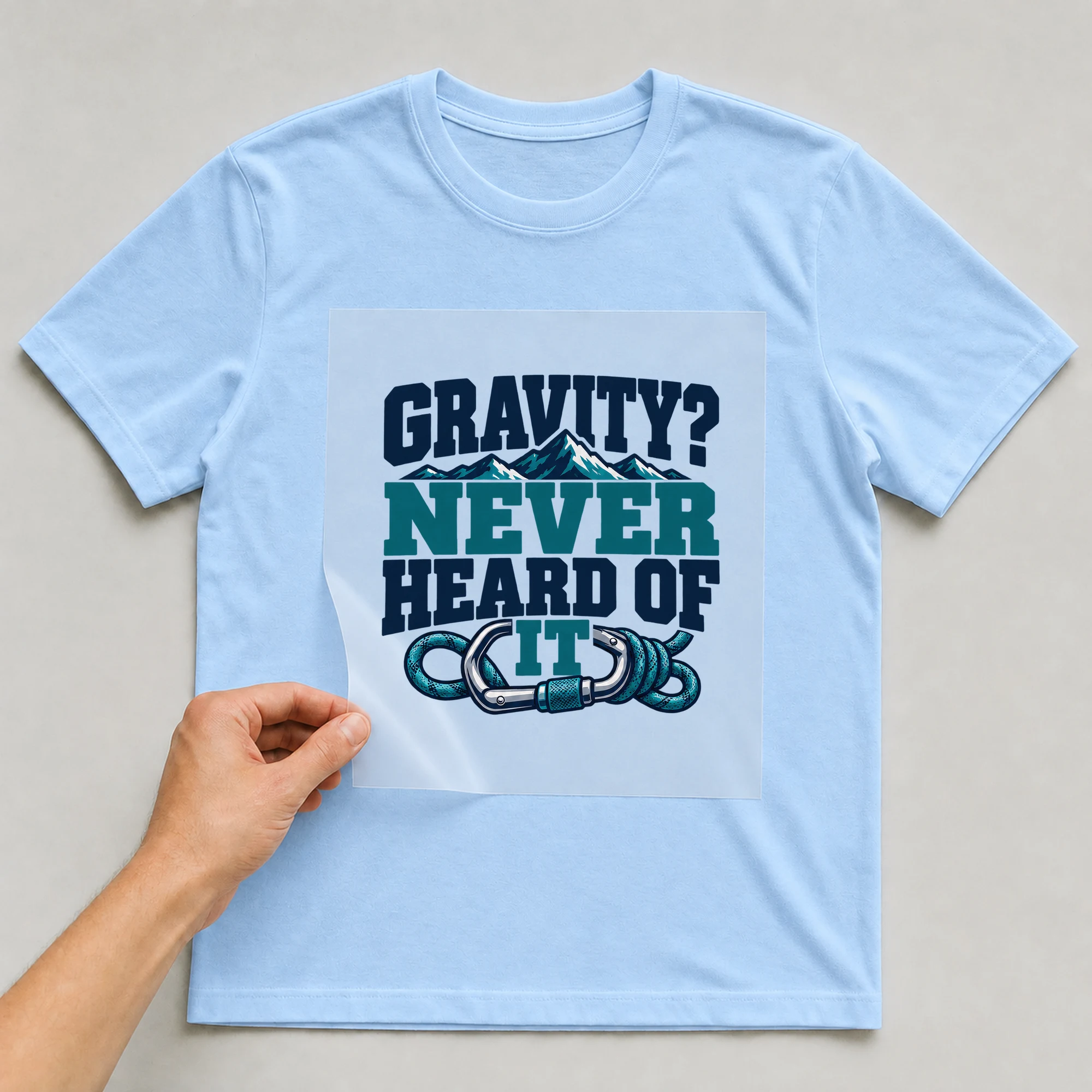 Bügelbild „Gravity? Never Heard Of It“ auf babyblauem T-Shirt, Folie wird aufgelegt