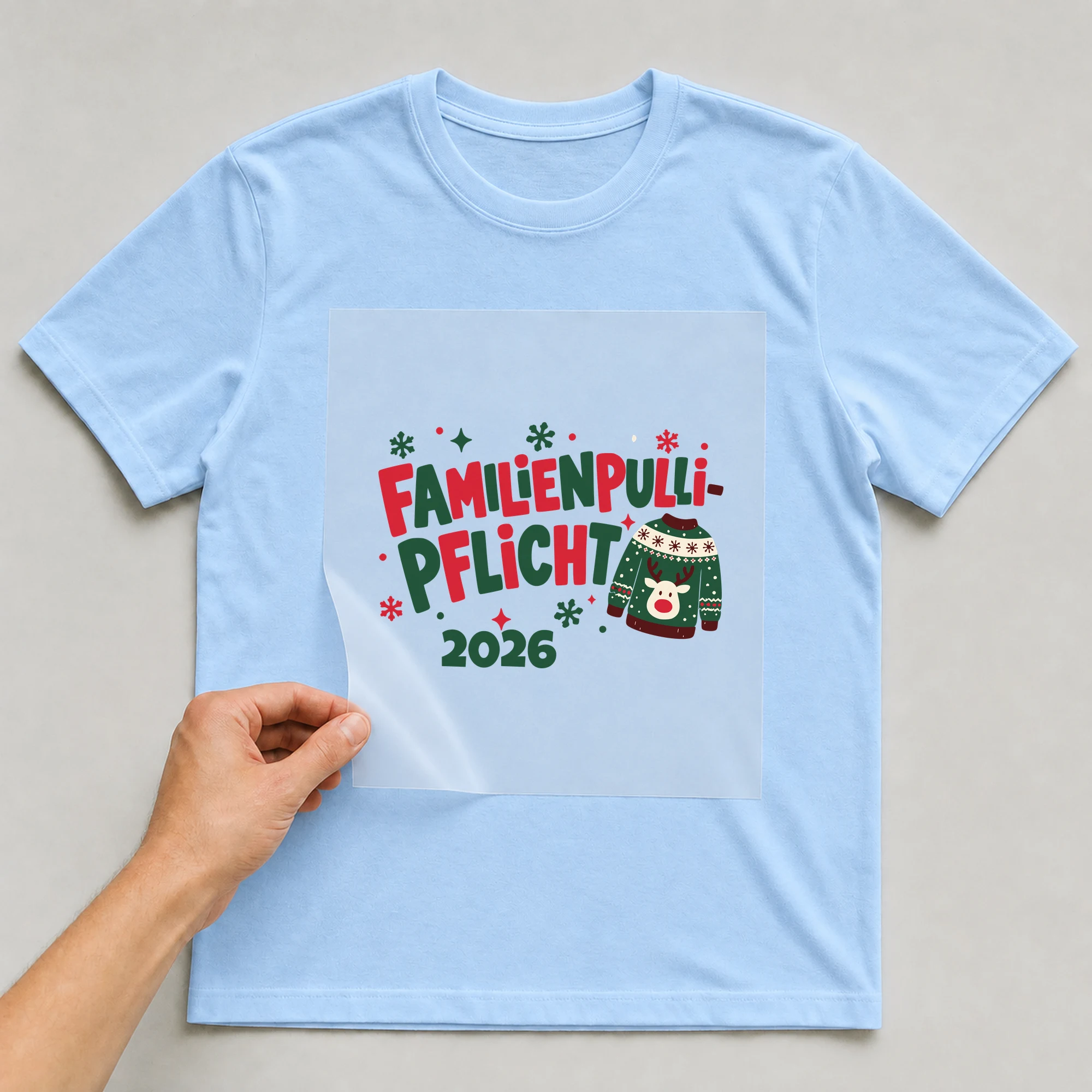 Bügelbild Familienpulli-Pflicht mit Jahr auf hellblauem T-Shirt, Folie wird aufgelegt